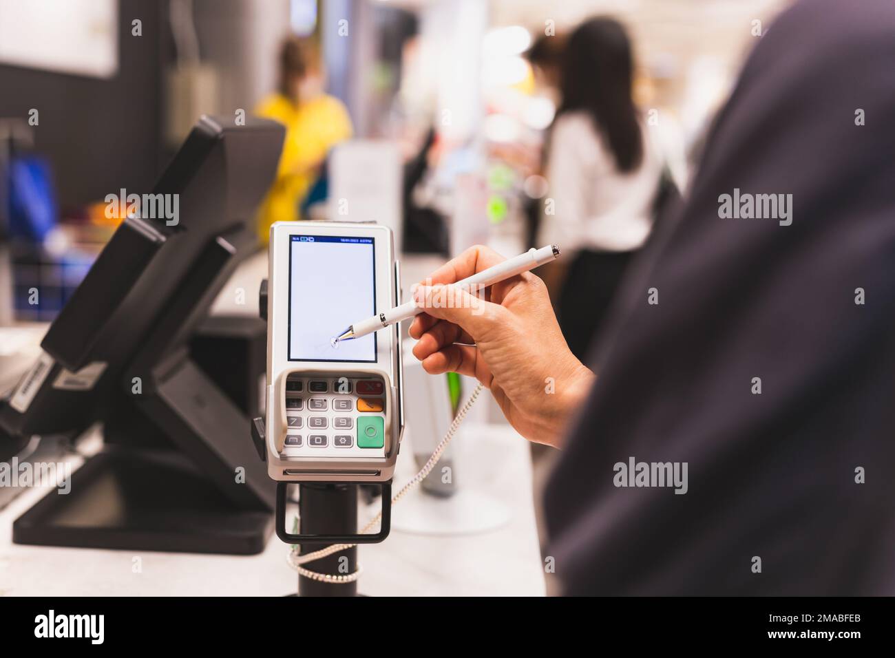 Frauen von Kunden, die auf einem Touchscreen eines Kreditkartentransaktionsautomaten auf dem Abendmarkt signieren. Stockfoto
