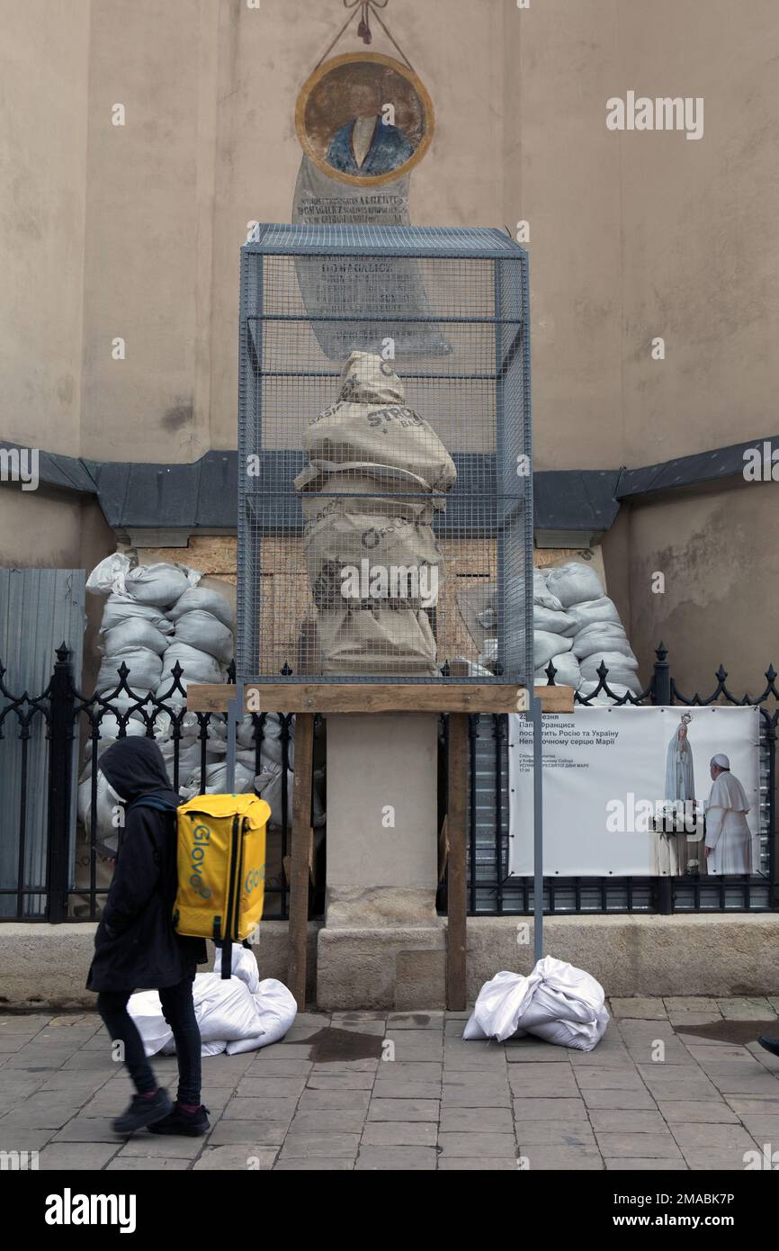 16.04.2022, Ukraine, Oblast, Lemberg - Eine Kirchenstatue außerhalb der Kathedrale Basilika der Himmelfahrt der Heiligen Jungfrau Maria ist durch san geschützt Stockfoto