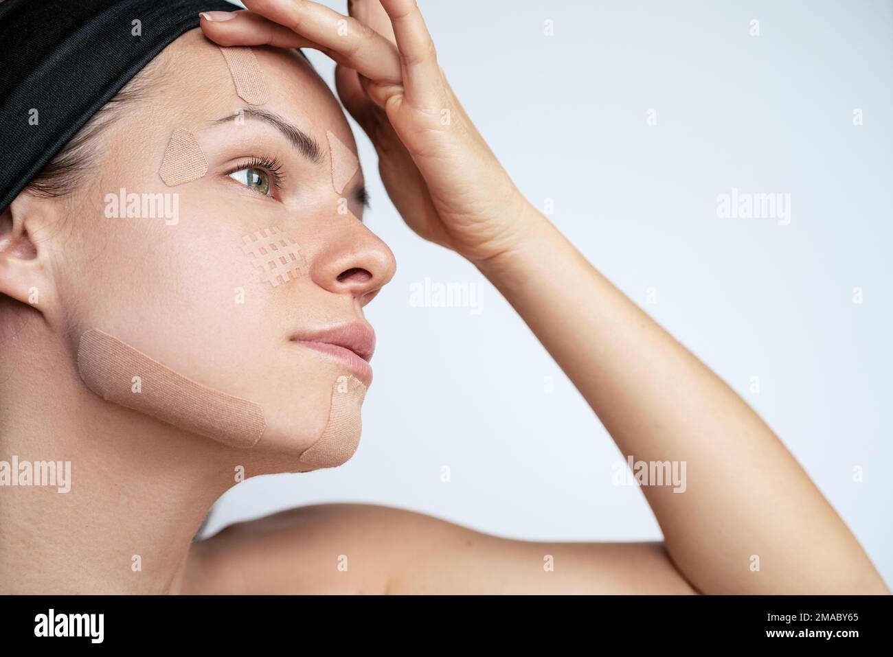 Erwachsene Frau kleben Kinesio-Bänder auf ihr Gesicht, Falten kleben. Stockfoto