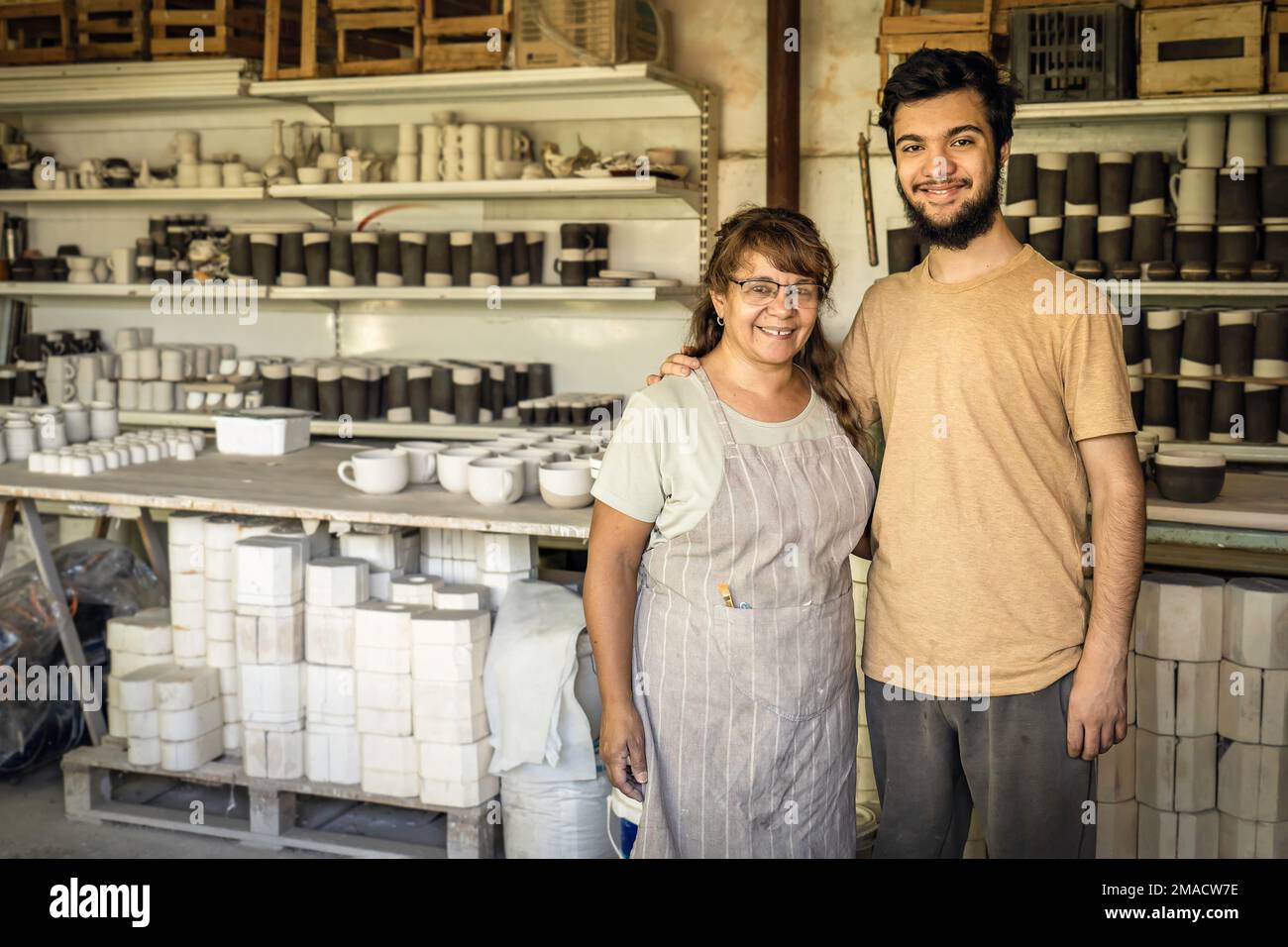 Frau und Sohn lächelten und schauten in die Kamera im Keramikstudio. Familiengeschäft. Stockfoto