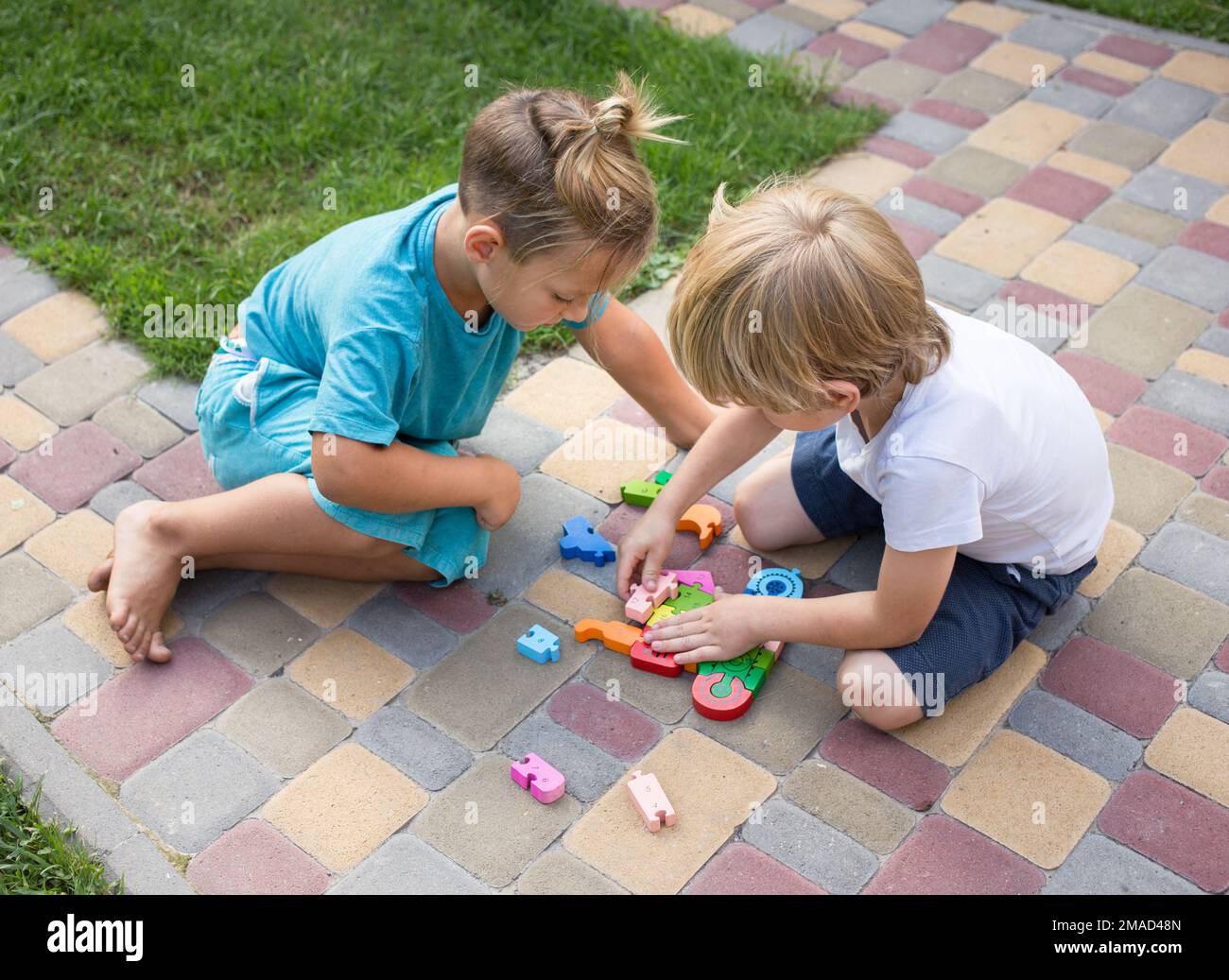 Zwei neugierige Jungs, Freunde, Brüder im Vorschulalter spielen mit einem Puzzle. Schulvorbereitung, Entwicklung der Logik, Kindheit, Kommunikation Stockfoto