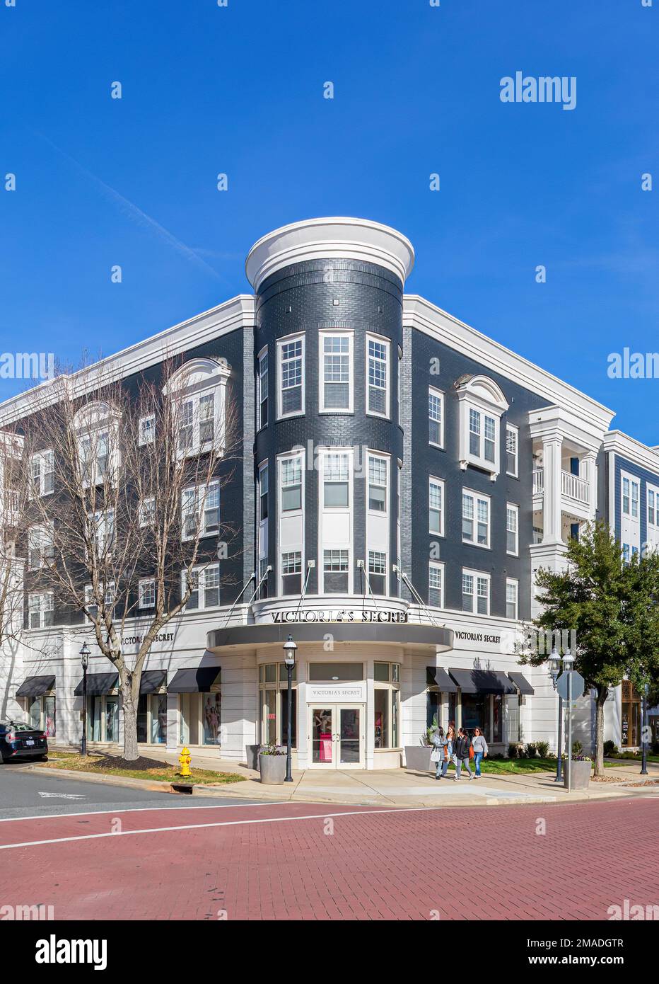 BIRKDALE VILLAGE, HUNTERSVILLE, NC, USA -15. JANUAR 2023: Eleglant-Eckgebäude mit Victoria's Secret. Vier Frauen gehen vor dem Gebäude. Stockfoto