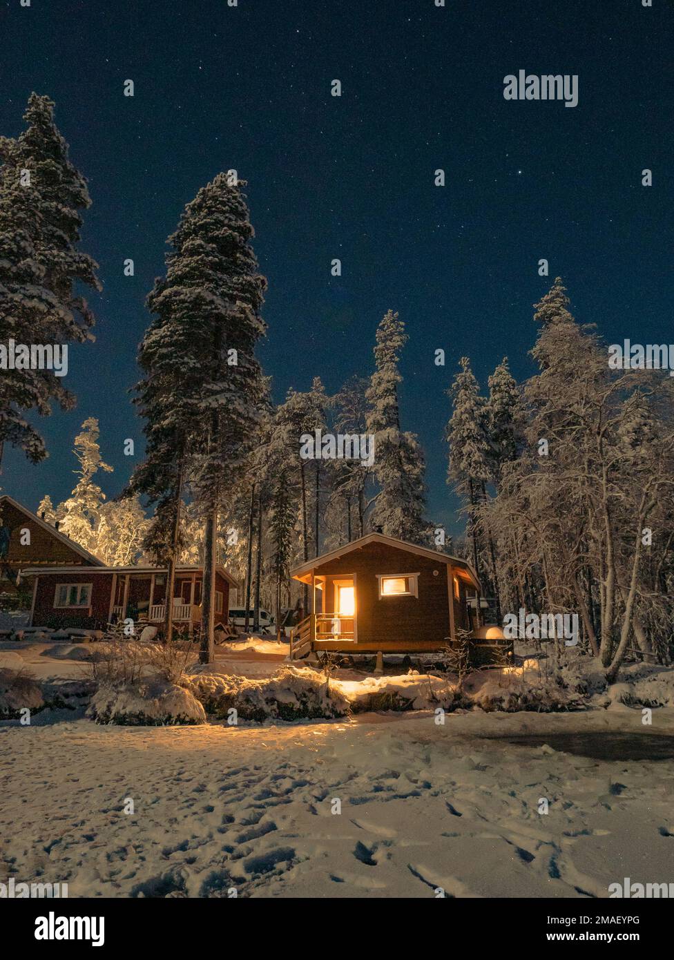 Rote Holzkabine im Winterwald bei Nacht in Rovaniemi, Finnland. Stockfoto