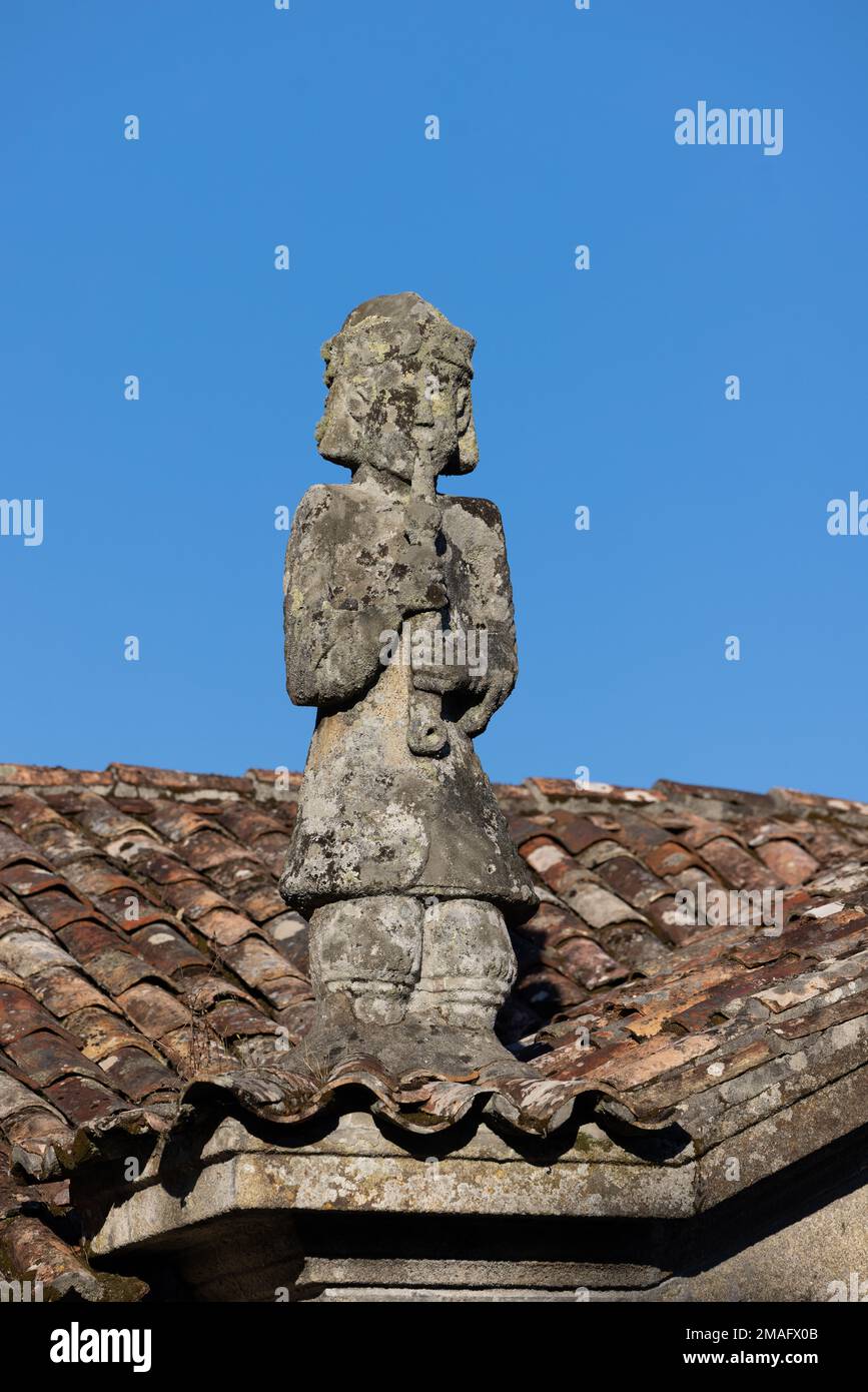 Granitskulptur eines Flötisten auf dem Dach einer Kirche in Galicien, Spanien Stockfoto
