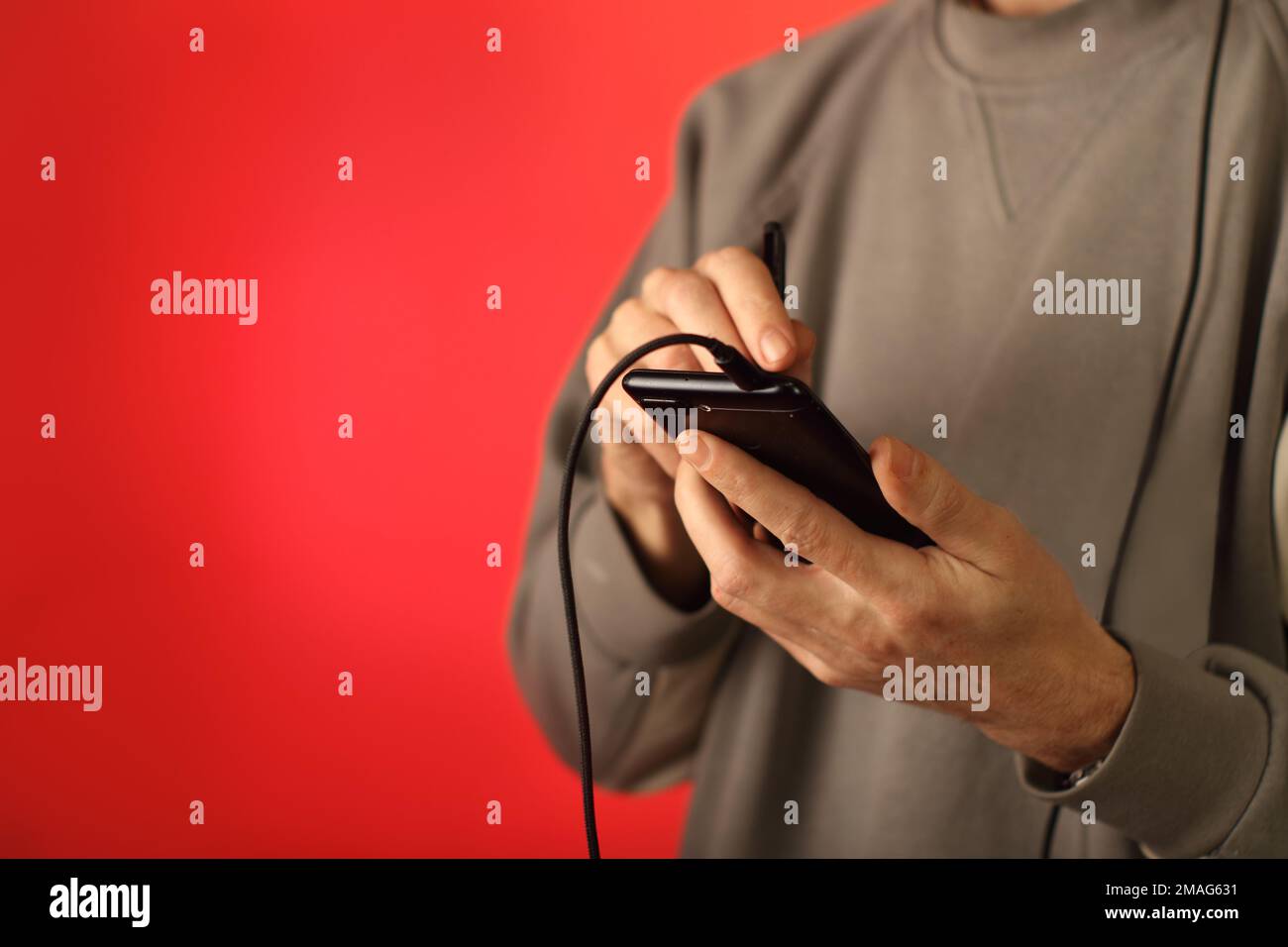 Person, die auf einem Smartphone mit einem Eingabestift an einer farbigen Wand schreibt Stockfoto