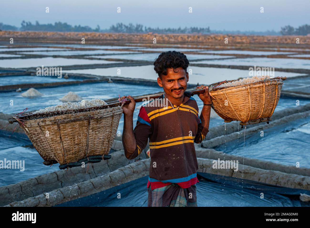 Ein Bauer entlädt Rohsalz auf dem Salzfeld in Chittagong, Bangladesch. Dieses Foto wird am Ziel von Banshkhali Upazila in der Division Chittagong aufgenommen. Die Salzindustrie, eine der größten arbeitsintensiven Hüttenindustrien Bangladeschs, nimmt fast 5 Millionen Menschen direkt oder indirekt auf. Die gesamte Wertschöpfungskette der Salzindustrie in Bangladesch umfasst im Wesentlichen zwei Teilsektoren: Den Raffinierungsprozess, der von Salzmühlen betrieben wird, und den Rohsalzproduktionsprozess, an dem ein erheblicher Teil der Randbauern der Küste Bangladeschs beteiligt ist. ( Stockfoto