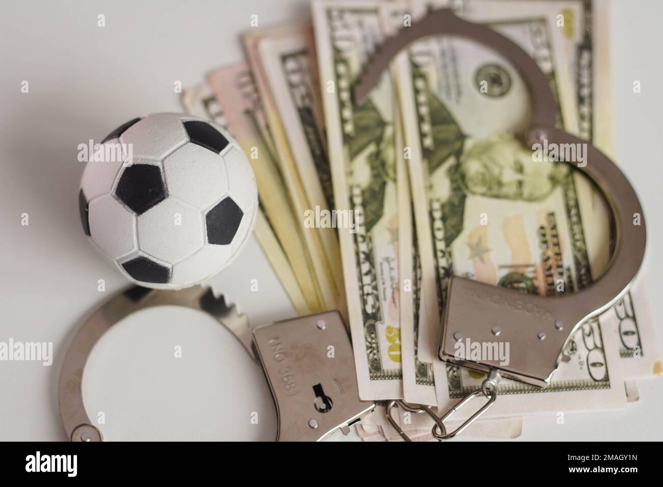 Fußball mit Geld und Handschellen. Korruption im Fußball-, Glücksspiel- und Wettbegriff. Stockfoto