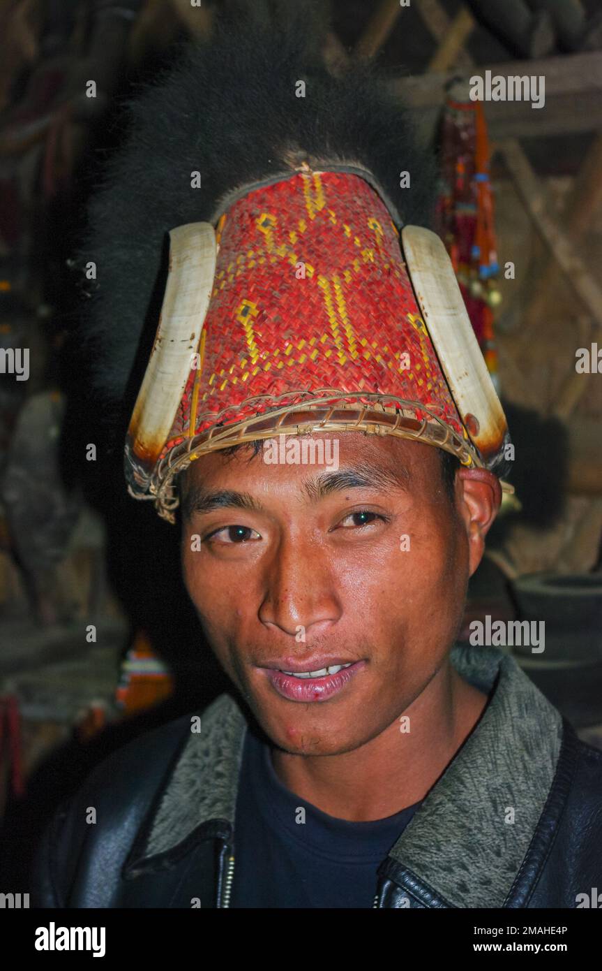 Mon, Nagaland, Indien - 03 02 2009 : Innenporträt des jungen Naga Konyak-Stammes mit traditionellem rotem Bambus und Rohrhut mit Stoßzähnen und Fell Stockfoto