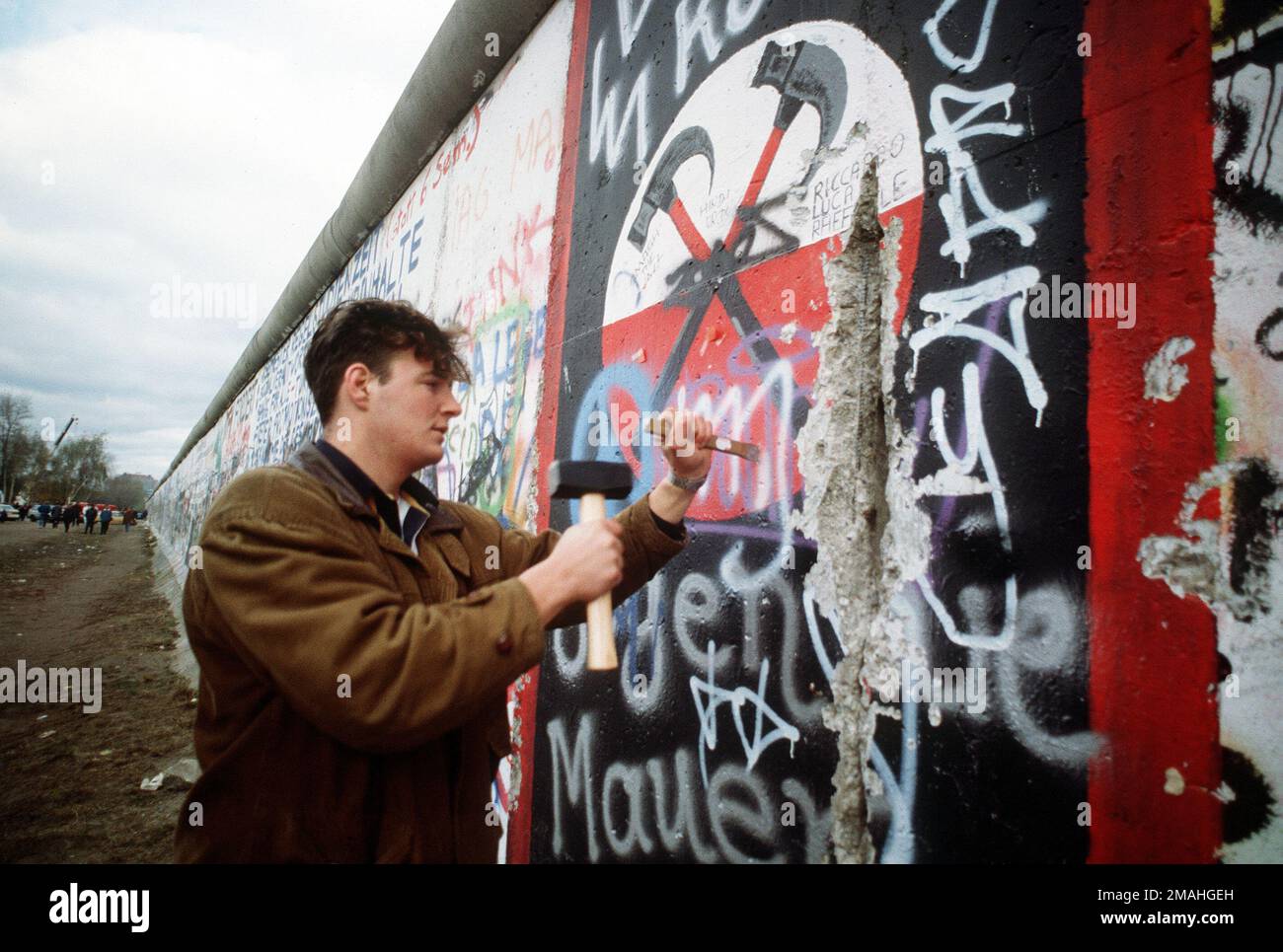 Ein westdeutscher Mann verwendet Hammer und Meißel, um ein Stück der Berliner Mauer als Souvenir abzuschlagen. Ein Teil der Mauer wurde bereits am Potsdamer Platz abgerissen. Basis: Berlin Land: Deutschland / Deutschland (DEU) Stockfoto