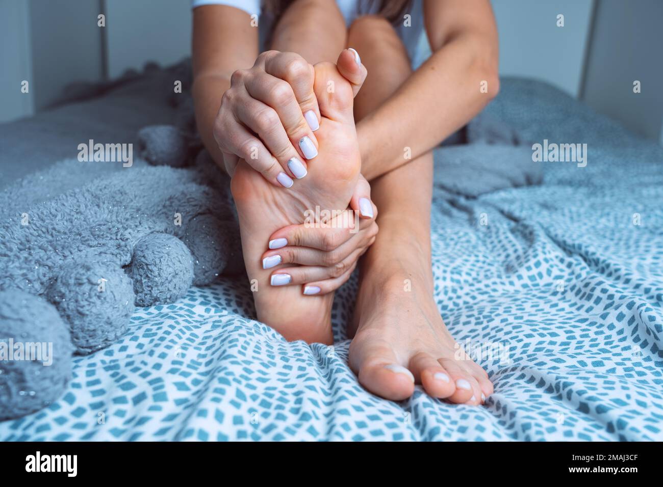 Frau, die an Fußschmerzen oder Fußschmerzen leidet und schmerzhafte Füße massiert. Beinkrämpfe, Schmerzen in den Beinen oder Muskelkrämpfe Stockfoto