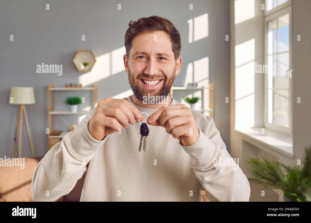 Porträt eines glücklichen, fröhlichen, aufgeregten Mannes, der den Schlüssel zu seinem neuen Haus oder Apartment hält Stockfoto