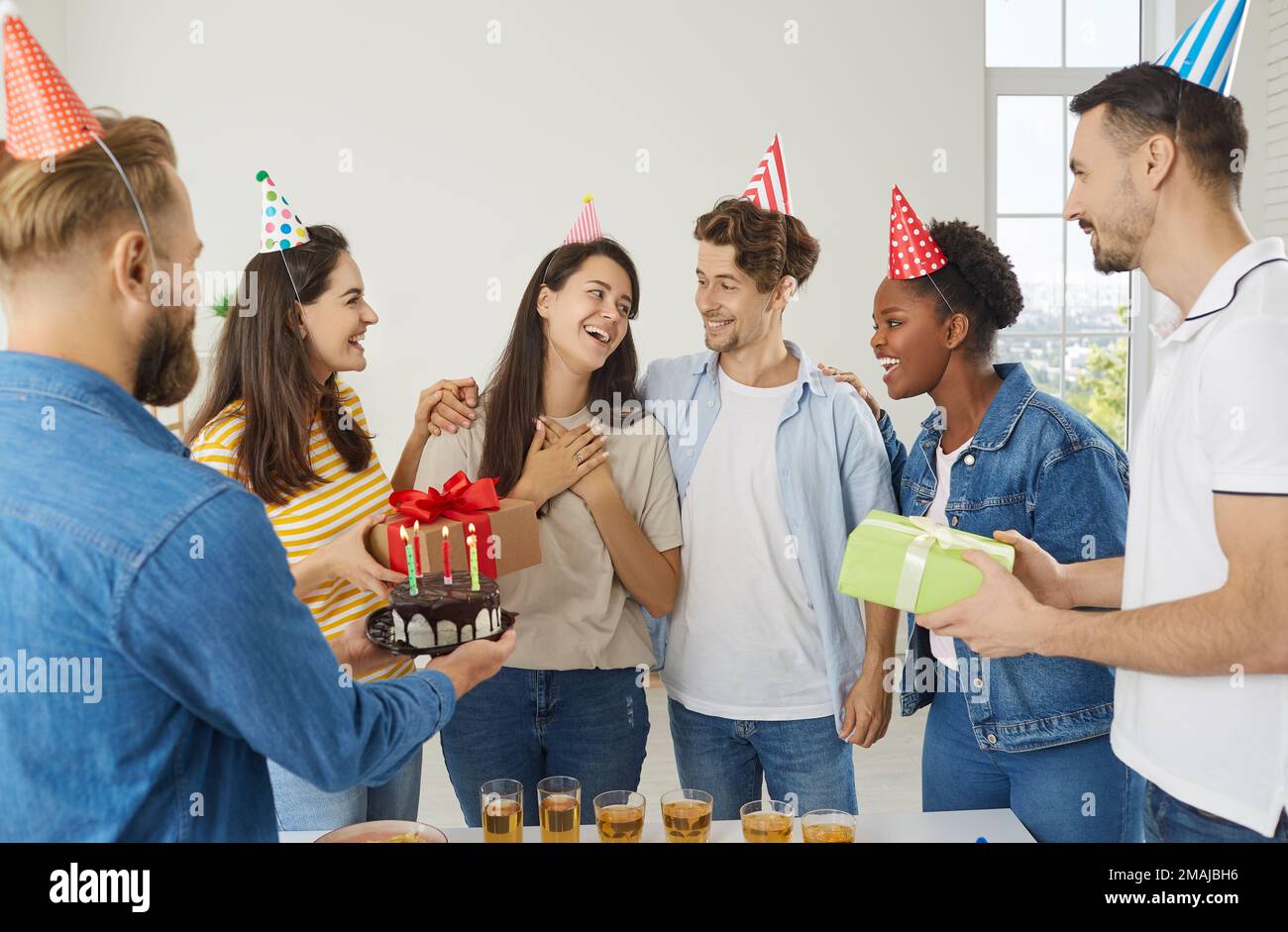 Eine Gruppe von freudigen, multirassischen Menschen, die Spaß auf einer Geburtstagsparty ihres Freundes haben Stockfoto