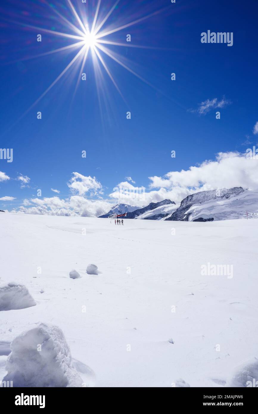 Ein Schweizer Hubschrauber mit roten und weißen Sternen steht auf dem Aletsch-Gletscher mit Blick aus dem Tiefwinkel. Helikopter, blauer Himmel mit Wolken. Grindelwald, Schweiz Stockfoto