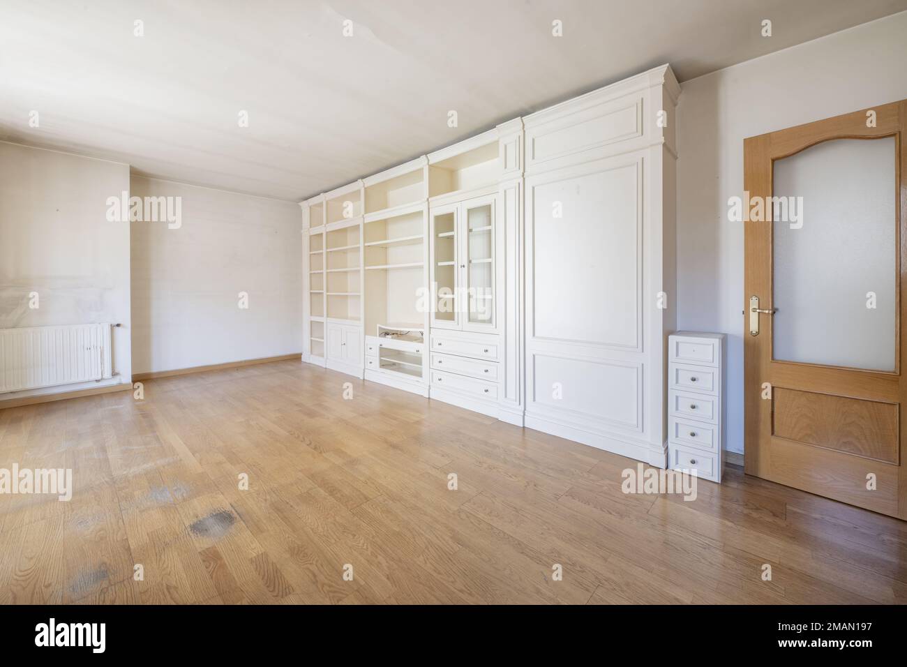 Wohnzimmer eines leeren Hauses mit Eichentüren und einem maßgeschneiderten, weiß lackierten Holzregal Stockfoto