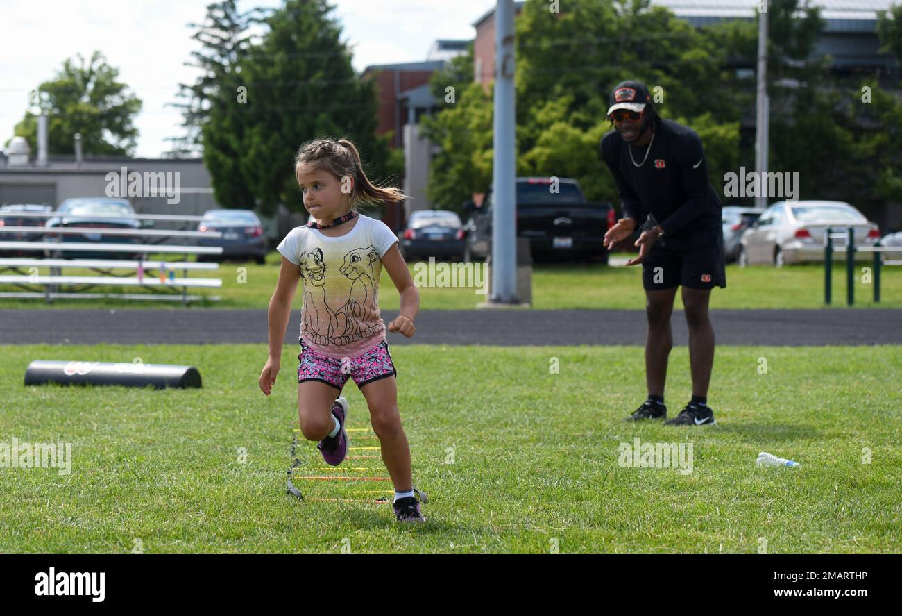Cincinnati Bengals Cornerback Allan George jubelt einen Luftwaffenstützpunkt Wright-Patterson, Ohio, Militärkind in der VON DER USO gesponserten Cincinnati Bengals Football Skills Clinic, 3. Juni 2022. Eine Gruppe bengalischer Neulinge aß mit Flugzeugen zu Mittag, besichtigte die Basis und leitete die Skills-Klinik für 99 Wright-Patt-Militärkinder. Stockfoto