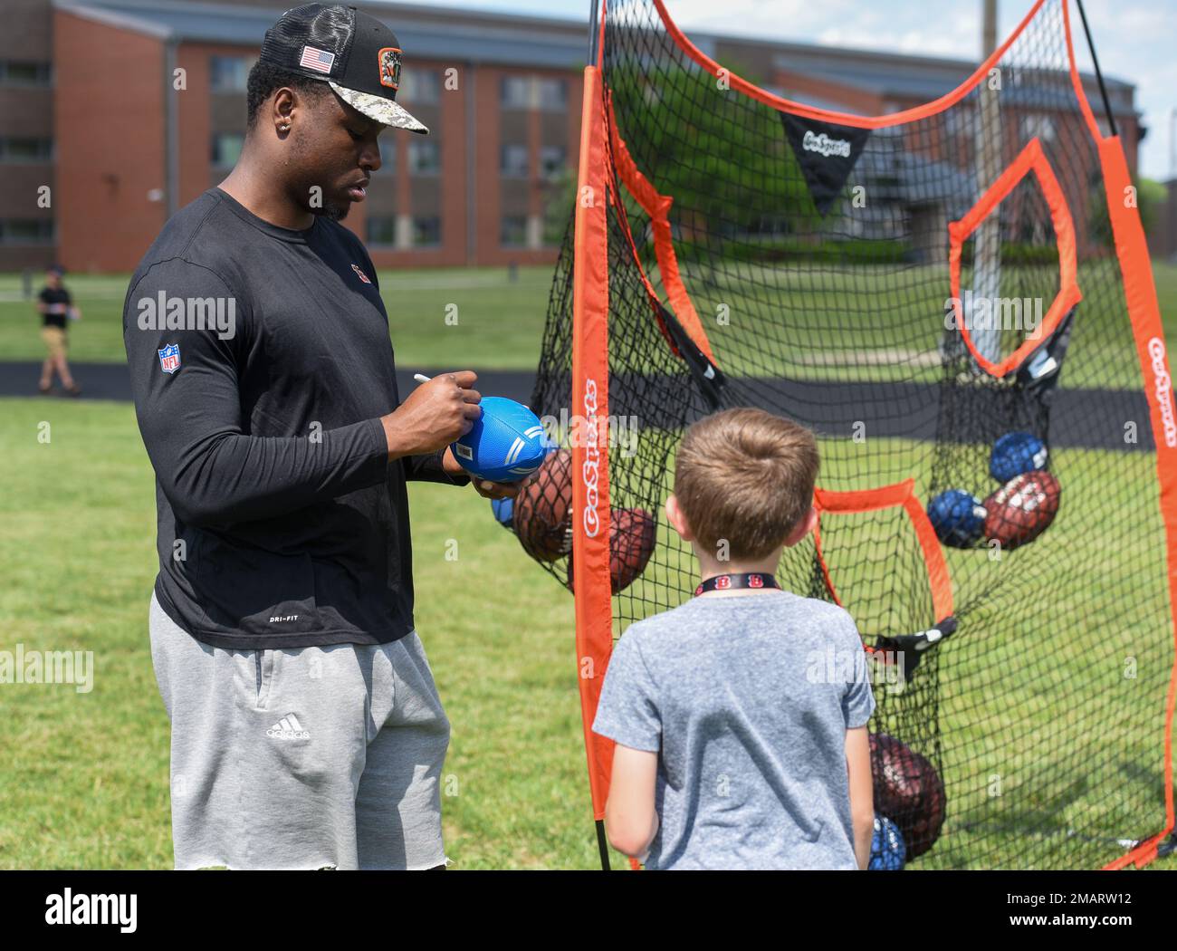 Cincinnati Bengals Defensive End Jeff Gunter unterzeichnet einen Fußball für eine Wright-Patterson Air Force Base, Ohio, ein Militärkind in der von der USO gesponserten Cincinnati Bengals Football Skills Clinic, 3. Juni 2022. Eine Gruppe von bengalischen Anfängern hatte ein Mittagessen mit Airmen, tourte durch die Basis und leitete die Skills Clinic für 99 Wright-Patt-Militärkinder. 88 ABW, BENGALS, NFL, USAF, WPAFB, Stockfoto