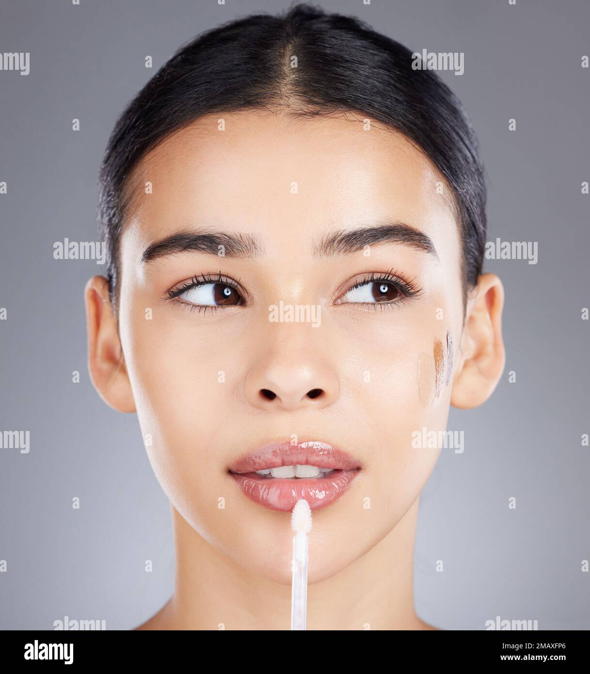 Frau, Lipgloss und Gesichts-Make-up isoliert auf grauem Hintergrund für Schönheit, Glanz oder Kosmetik. Wunderschönes weibliches Modell, das glänzt oder glänzt Stockfoto