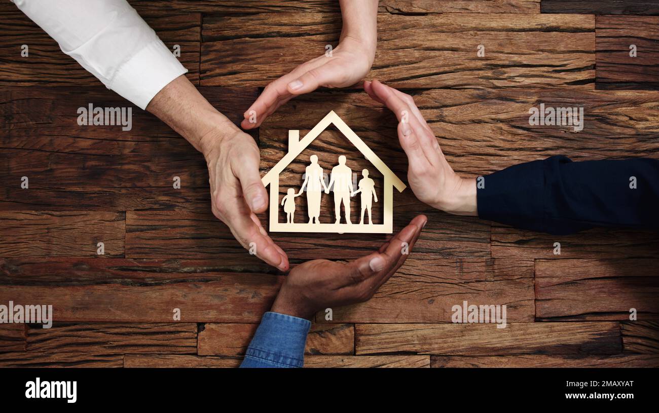 Schutz Für Familienpapier, Das Mit Den Händen Auf Dem Holzschreibtisch Herausgeschnitten Wurde Stockfoto