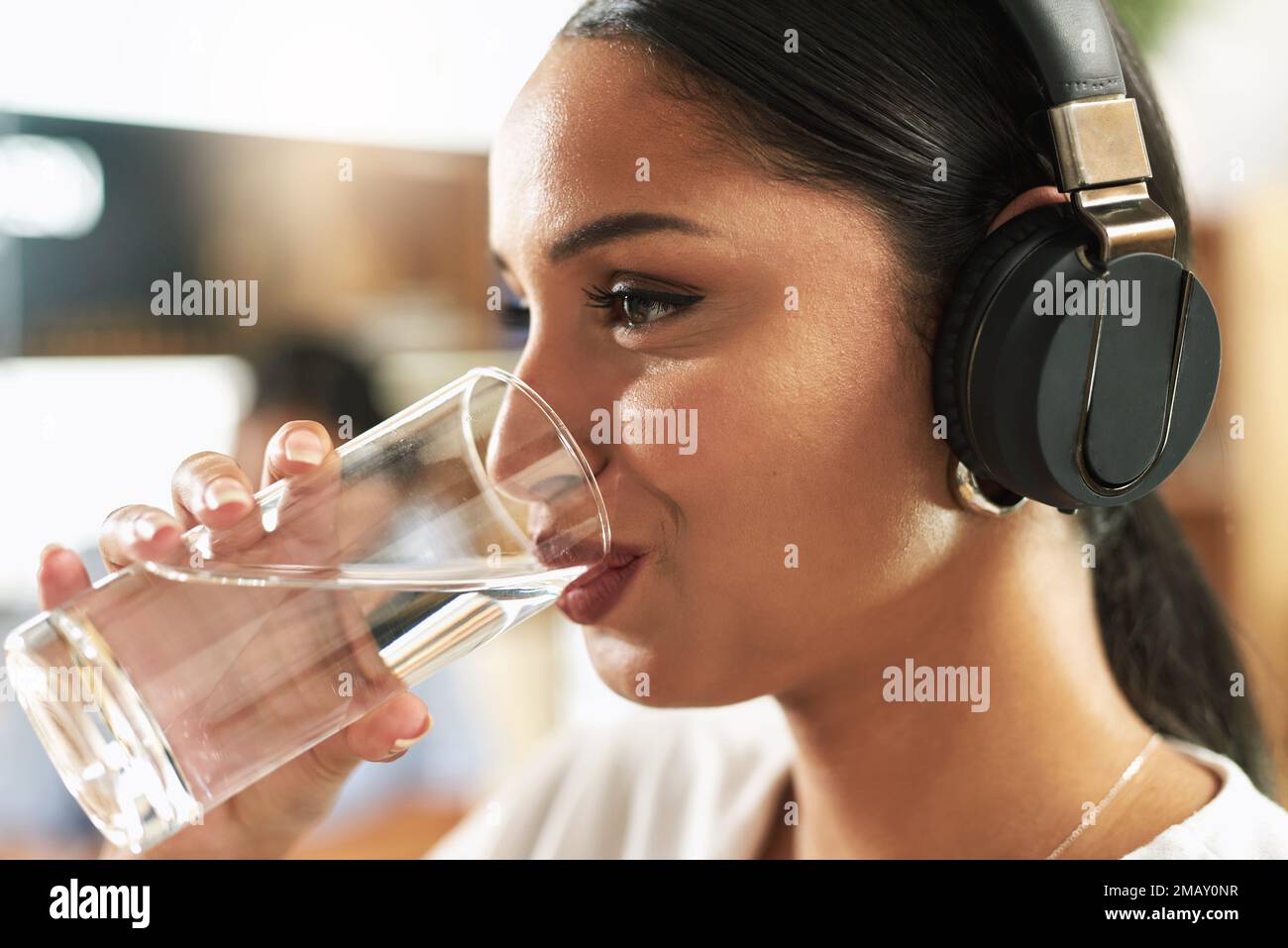 Ich halte meine Nieren in Form. Eine junge Geschäftsfrau, die bei der Arbeit ein Glas Wasser trinkt. Stockfoto