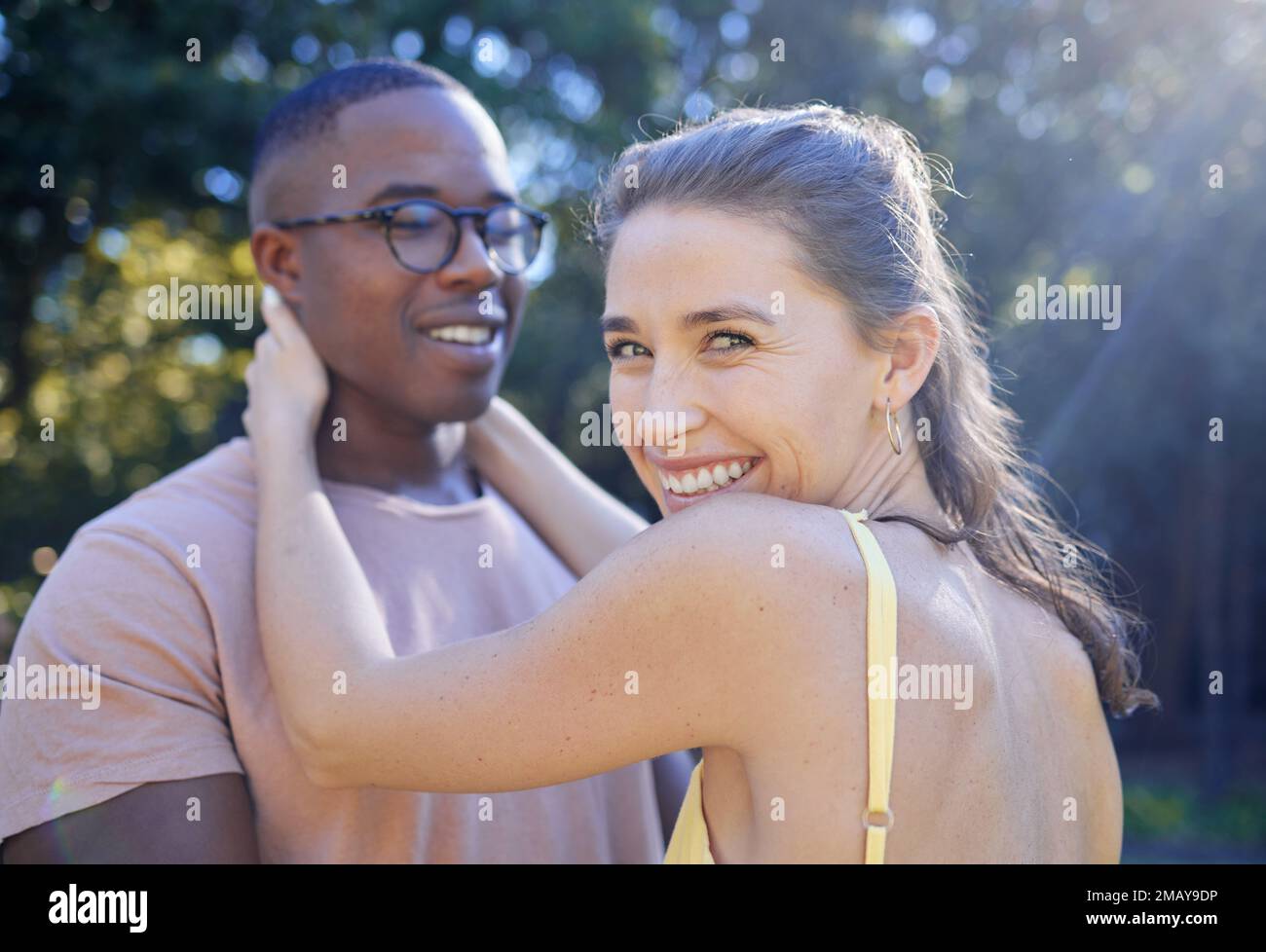 Glückliche Frau, Lächeln und gemischtrassiges Paar für Umarmung, Liebe oder Fürsorge für Sommerurlaub, Beziehung oder Bindung im Park. Ein weiblicher Häftling, der lächelt Stockfoto