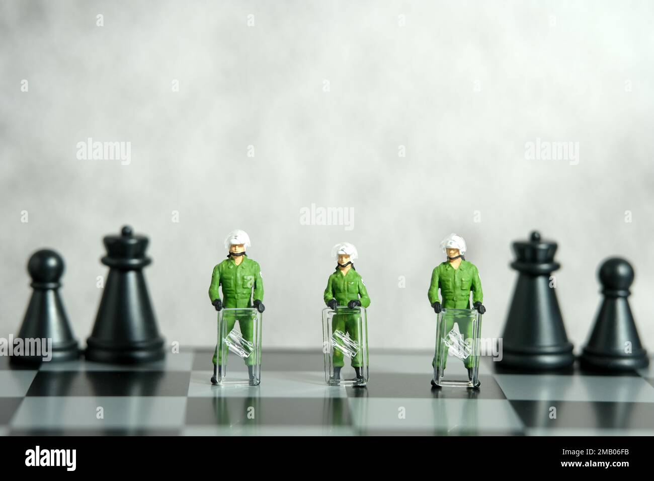 Miniatur-Menschen-Spielzeug-Figuren-Fotografie. Konzept der Schutzstrategie. Eine militärische Armee gegen Aufstände, die über dem Schachbrett steht. Bildfoto Stockfoto