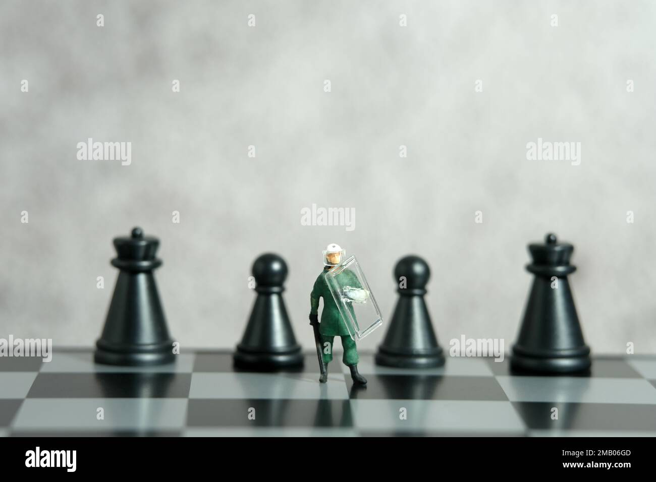 Miniatur-Menschen-Spielzeug-Figuren-Fotografie. Konzept der Schutzstrategie. Eine militärische Armee gegen Aufstände, die über dem Schachbrett steht. Bildfoto Stockfoto