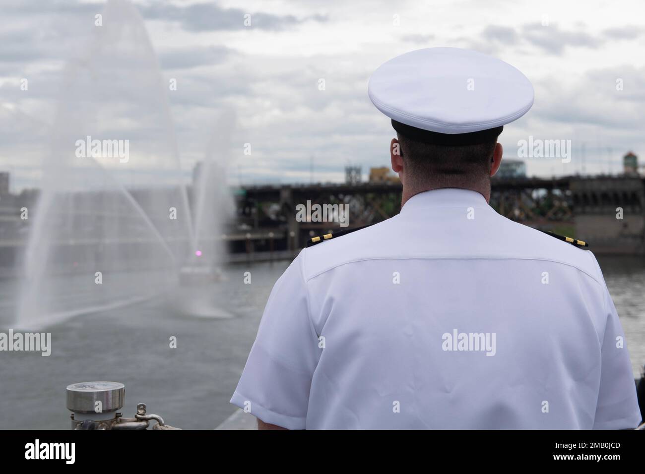 LT. Michael Tisdall, Ausbildungsoffizier des Zerstörers der Zumwalt-Klasse USS Michael Monsoor (DDG 1001), beobachtet, wie ein Feuerboot Wasser spritzt, während das Schiff in Portland, Oregon, ankommt, für Portland Fleet Week 2022, Juni 9. Die Portland Fleet Week ist eine feierliche Feier der Seeverkehrsdienste und bietet den Einwohnern Oregons die Gelegenheit, Matrosen, Marines und Küstenwachmänner zu treffen und die neuesten Möglichkeiten der heutigen Seeverkehrsdienste aus erster Hand zu erleben Stockfoto