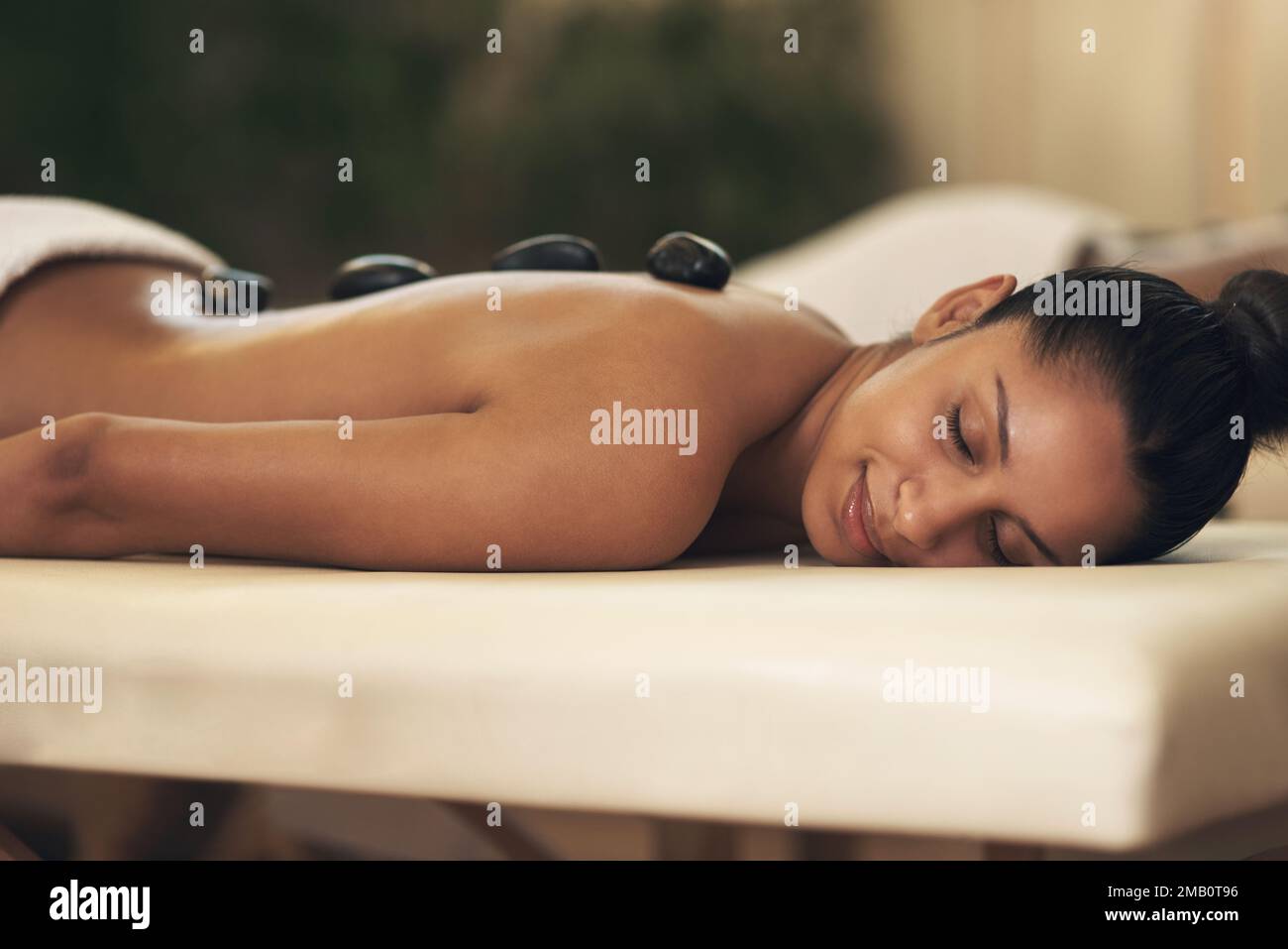 Ein Wellness-Tag wird Wunder für Ihr Wohlbefinden bewirken. Eine junge Frau, die eine Hot-Stone-Massage in einem Spa bekommt. Stockfoto