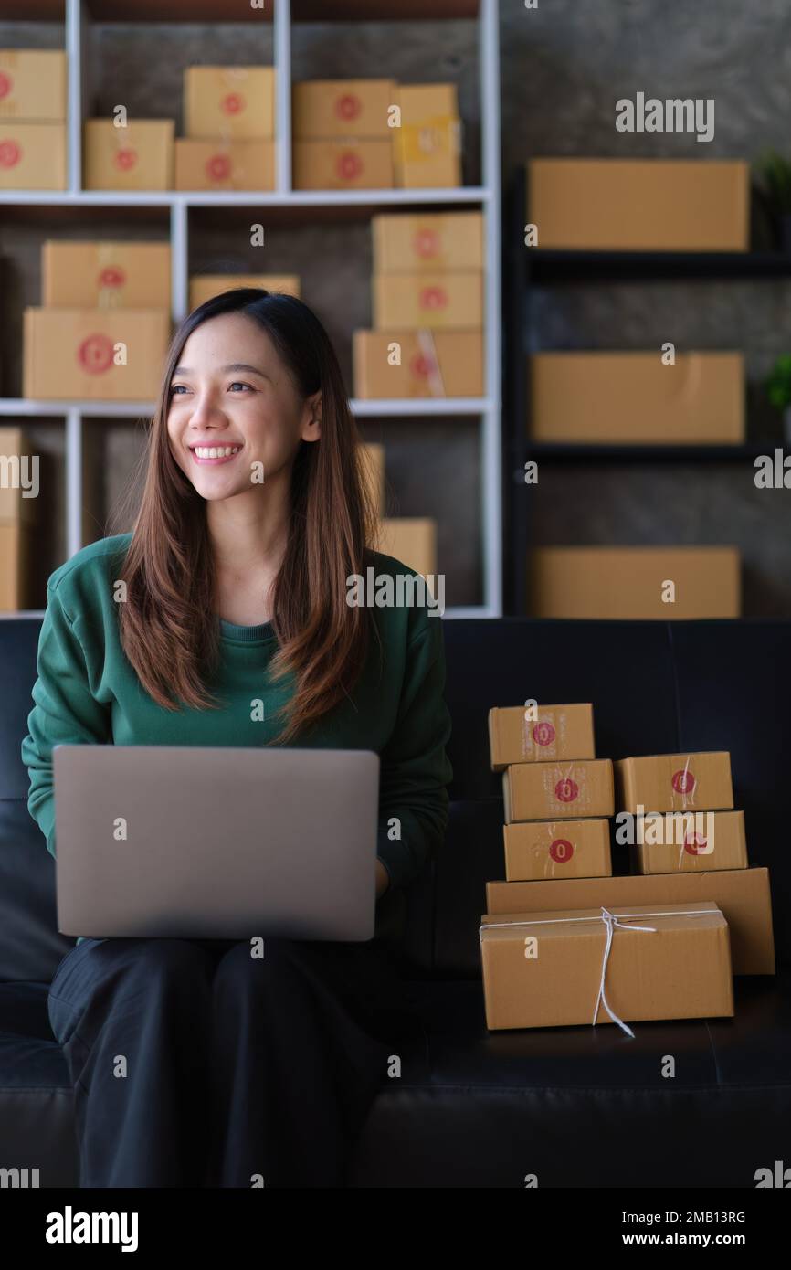 Porträt einer jungen asiatischen KMU, die zu Hause mit einer Kiste arbeitet. Unternehmer kleiner Unternehmen KMU und Lieferkonzept Stockfoto