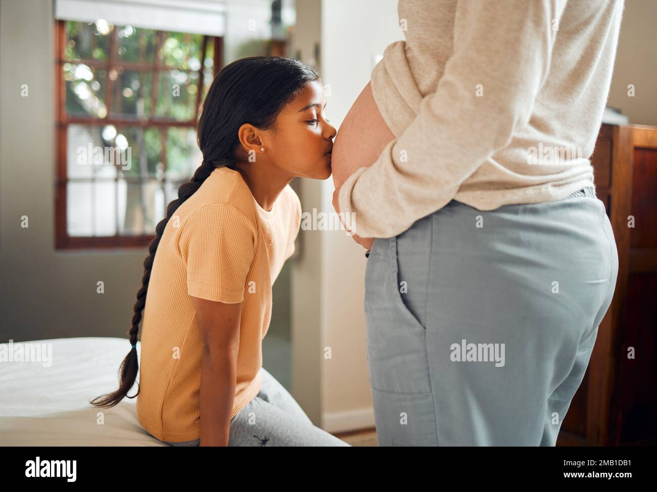 Schwanger, Familie und Bauch mit einer Tochter, die den Bauch ihrer Mutter küsst, während sie sich im Schlafzimmer ihres Zuhauses anfreundet. Kinder, mom und Schwangerschaft mit A Stockfoto