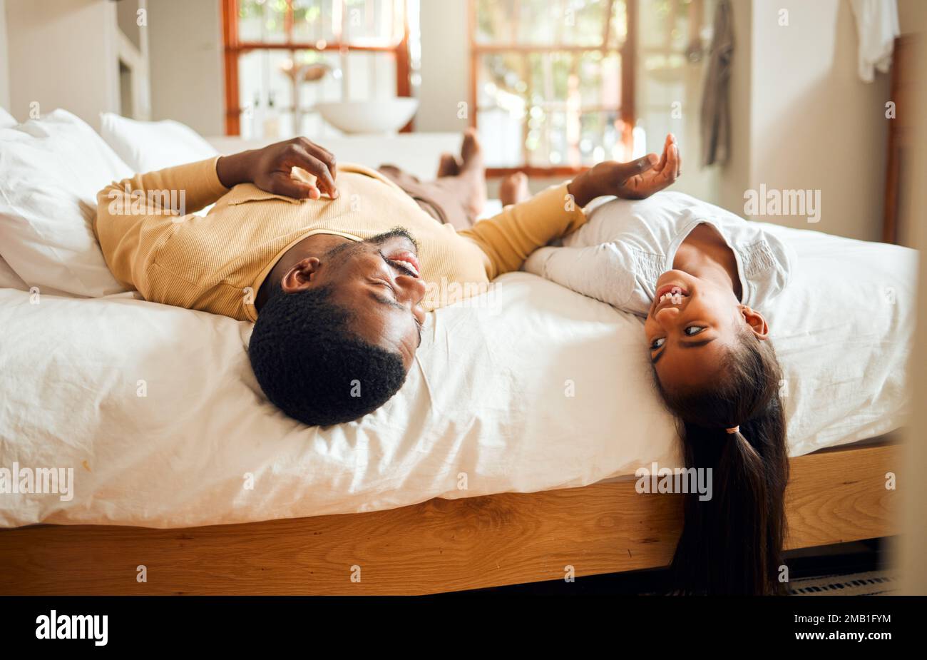Schwarze Familie, Kinder und Bett mit einem Vater und einer Tochter, die sich zusammentun, während sie in einem Schlafzimmer ihres Zuhauses liegen. Kinder, liebt und entspannt euch mit einem Mann und Stockfoto