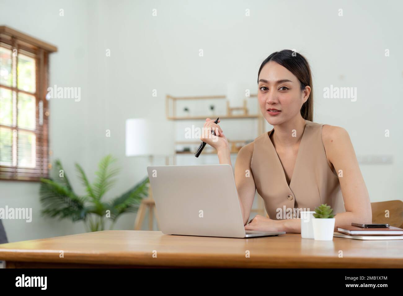 Porträt glückliches junges asiatisches Mädchen, das zu Hause mit einem Laptop arbeitet Stockfoto