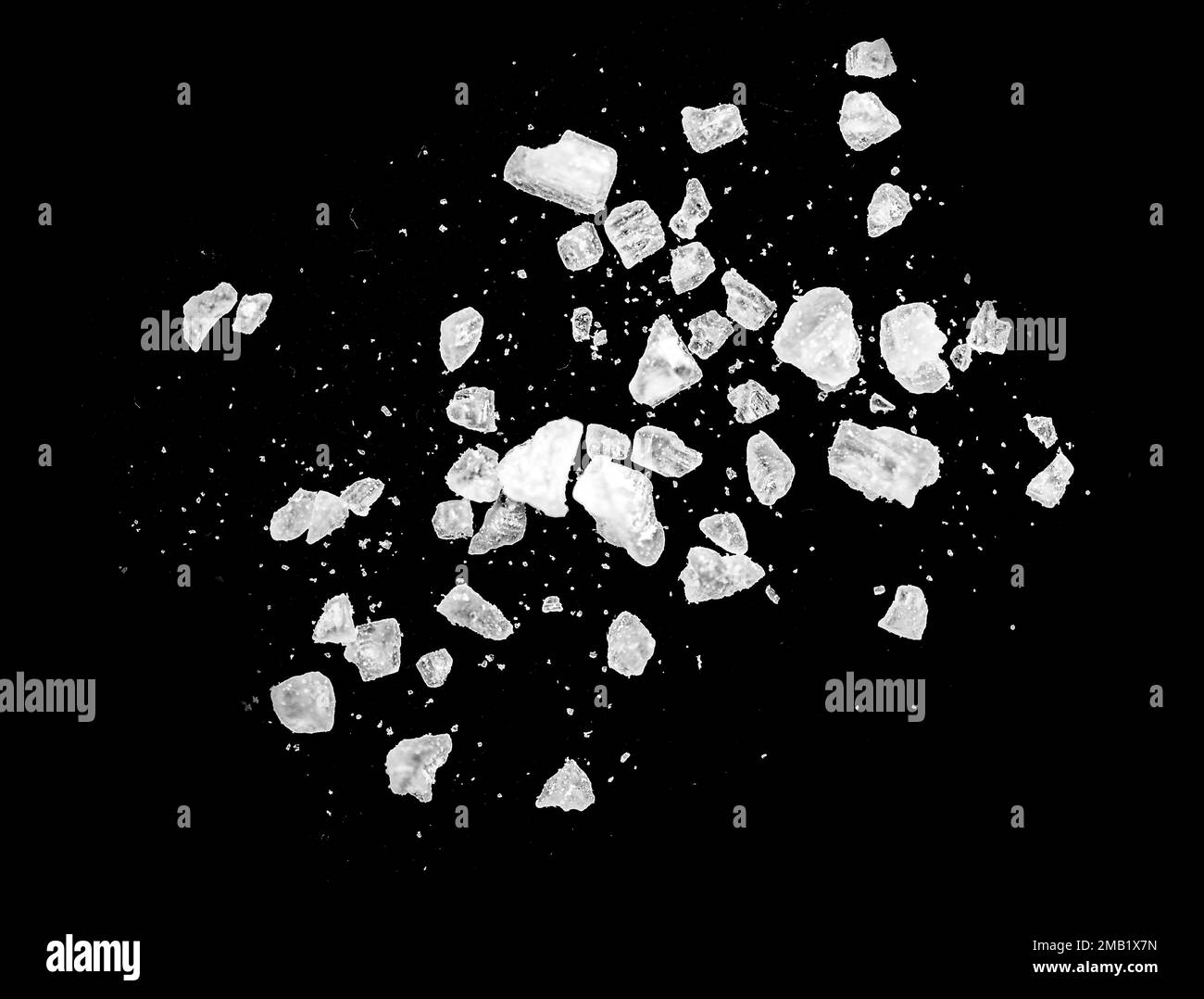 Makroaufnahme fallender und fliegender Salzkristalle, isoliert auf Schwarz Stockfoto