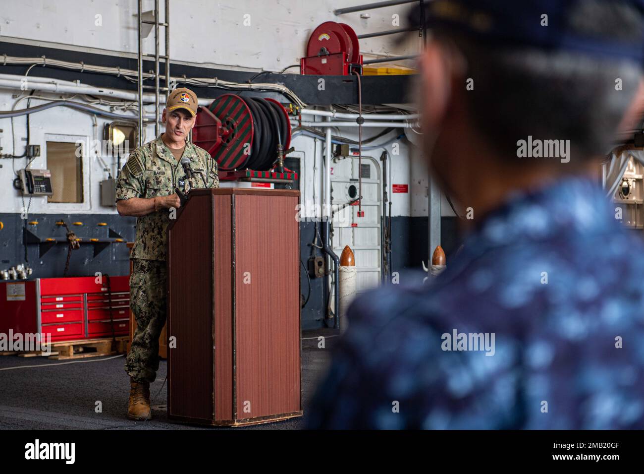 SASEBO, Japan (10. Juni 2022) Captain Greg Baker, Commodore, Amphibiengeschwader 11, spricht während seiner Zeremonie zum Befehlswechsel in der Hangarbucht des nach vorn eingesetzten Amphibienschiffs USS New Orleans (LPD 18). Das Amphibiengeschwader 11 ist im Zuständigkeitsbereich der US-amerikanischen 7.-Flotte tätig, um die Interoperabilität mit Verbündeten und Partnern zu verbessern und als einsatzbereite Eingreiftruppe zur Verteidigung von Frieden und Stabilität im Indo-Pazifik-Raum zu dienen. Stockfoto