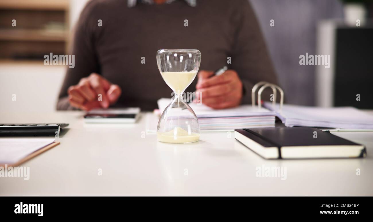 Verspätete Rechnung Und Rechnungsstellung Mit Hourglass Am Schreibtisch Stockfoto