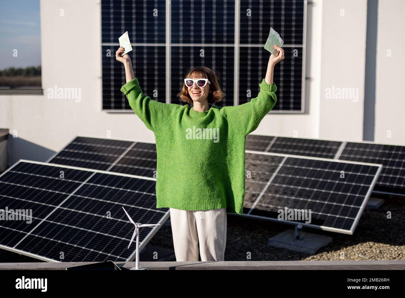 Glücklicher Hausbesitzer mit Geld in der Nähe des Solarkraftwerks Stockfoto
