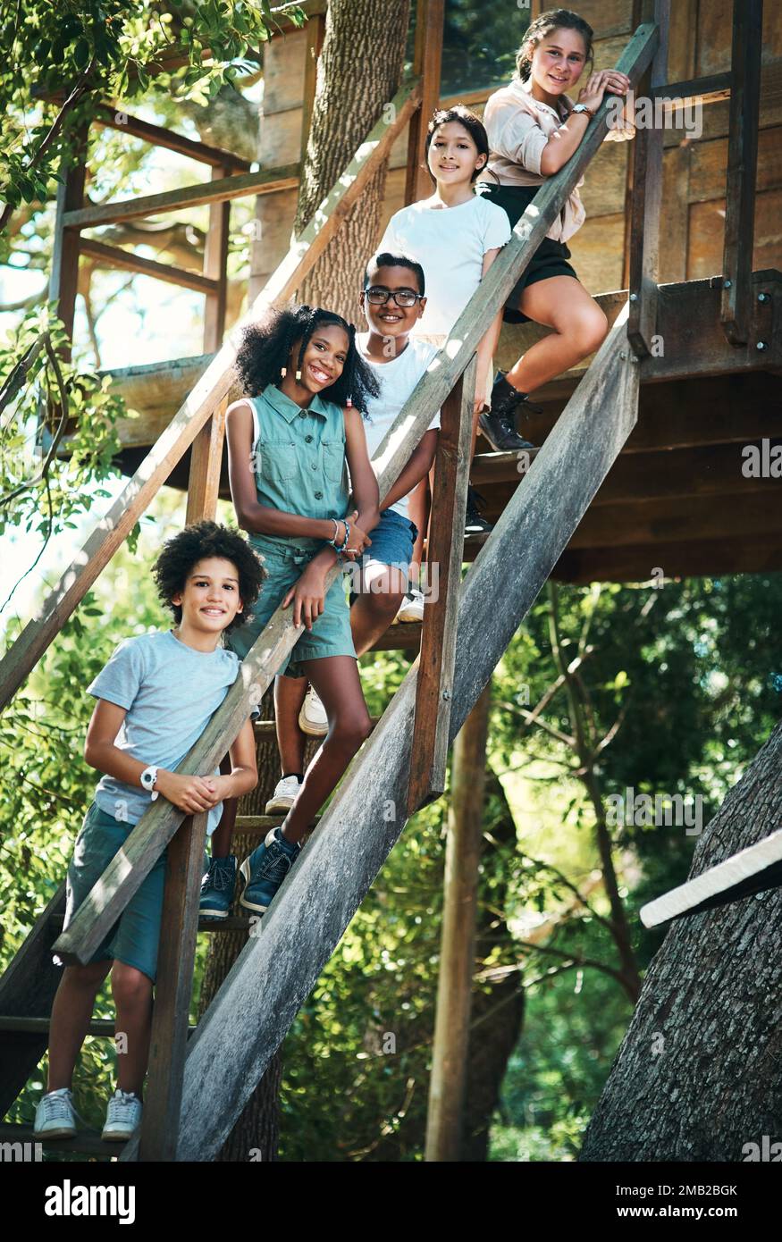 Möchten Sie eine Führung durch unser Baumhaus? Eine Gruppe Teenager, die neben einem Baumhaus im Sommercamp standen. Stockfoto