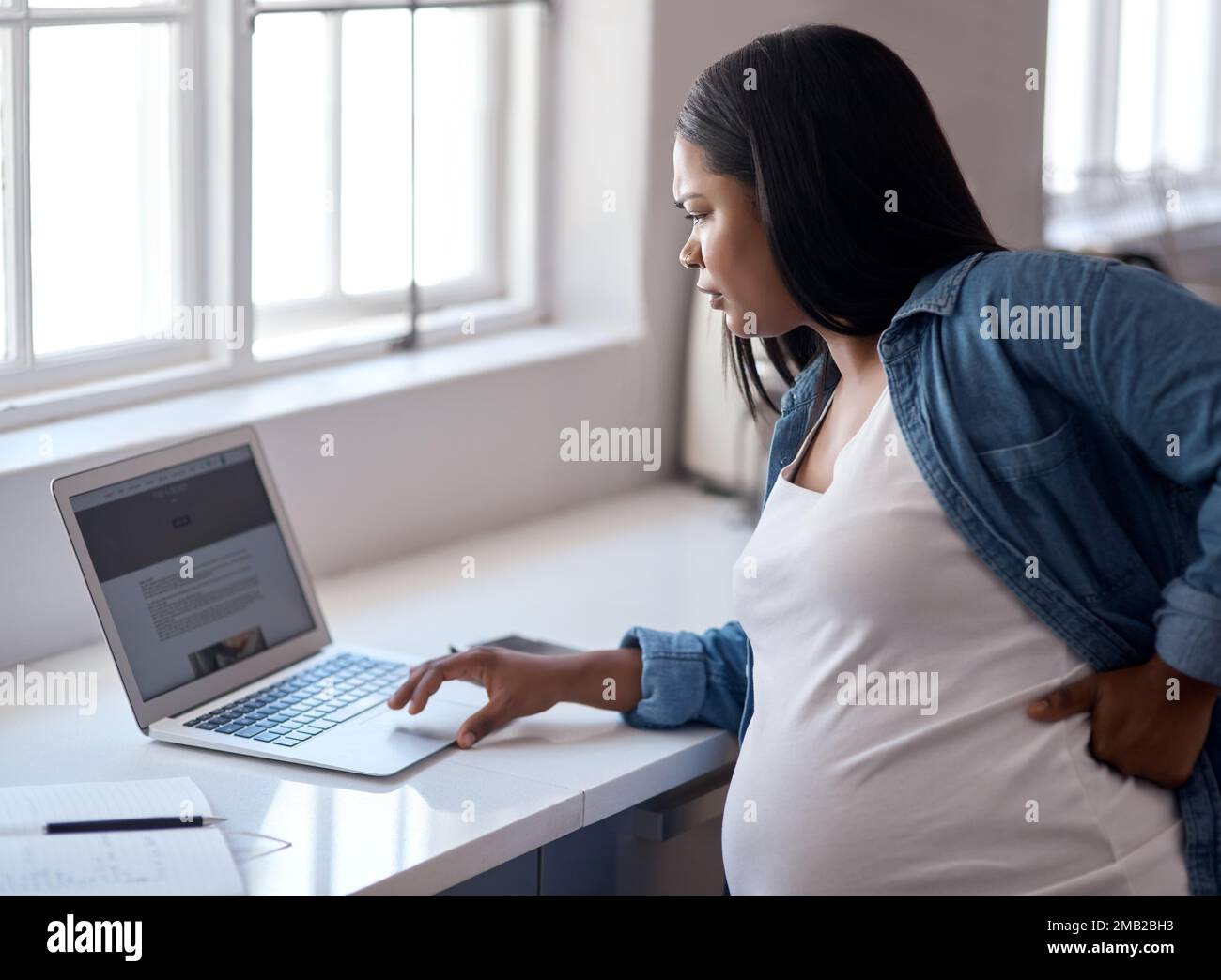Mutter zu werden, lässt mich meine Träume noch mehr verfolgen. Eine schwangere Frau, die ihren Laptop benutzt, während sie zu Hause sitzt. Stockfoto