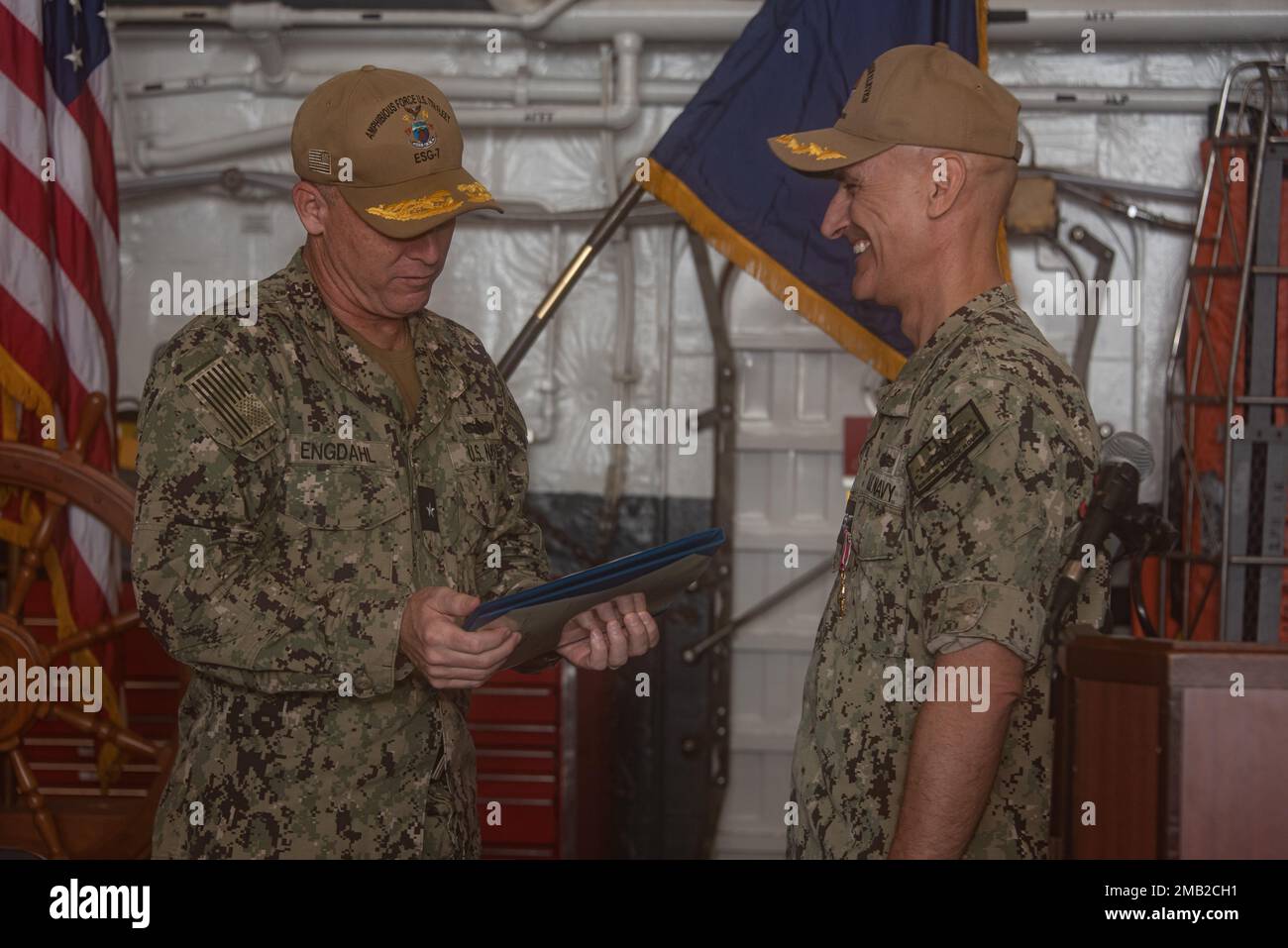 220610-N-XB010-1006 SASEBO, Japan (6. Juni 2022) Rear ADM. Christopher M. Engdahl, Commander, Task Force 76, Left, liest den Legion of Merit Award für Captain Greg Baker, Commodore, Amphibiengeschwader 11, während Bakers Zeremonie zum Befehlswechsel in der Hangarbucht des vorwärts eingesetzten Amphibienschiffs New Orleans (LPD 18). Das Amphibiengeschwader 11 ist im Zuständigkeitsbereich der US-amerikanischen 7.-Flotte tätig, um die Interoperabilität mit Verbündeten und Partnern zu verbessern und als einsatzbereite Eingreiftruppe zur Verteidigung von Frieden und Stabilität im Indo-Pazifik-Raum zu dienen. Stockfoto