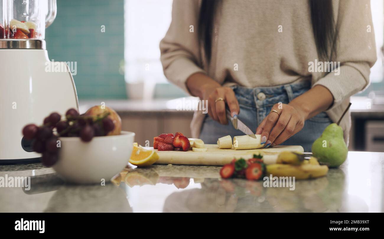 Nichts heilt den Körper besser als Obst. Eine unbekannte Frau schneidet Früchte, um einen Smoothie in ihrer Küche zuhause zuzubereiten. Stockfoto