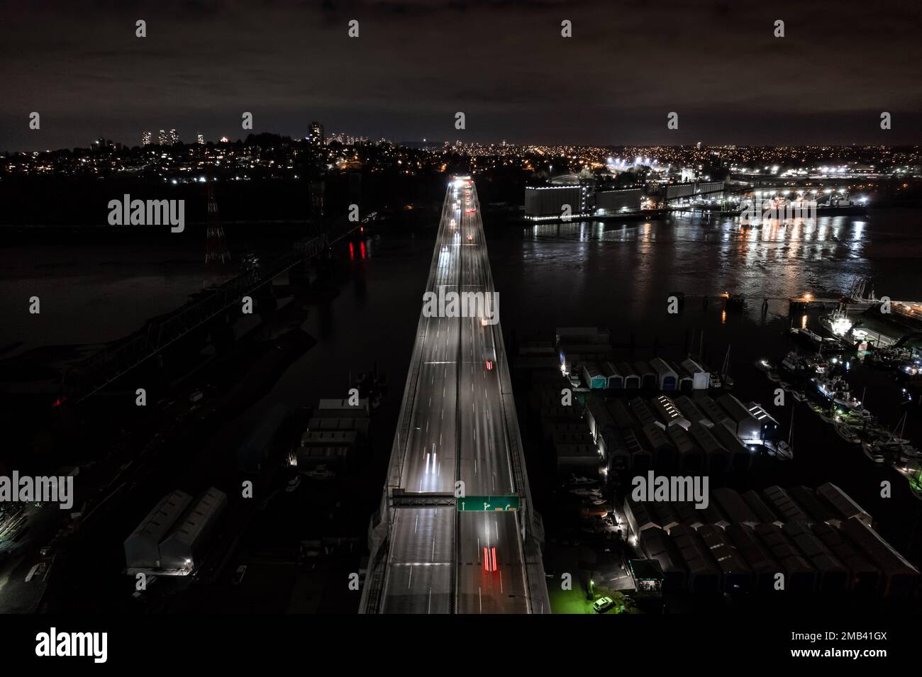Blick auf die Stadt bei Nacht, schneller Verkehr, Brücke über Wasser, Autos Lichtstreifen, Transportnetz, Straße. Stockfoto