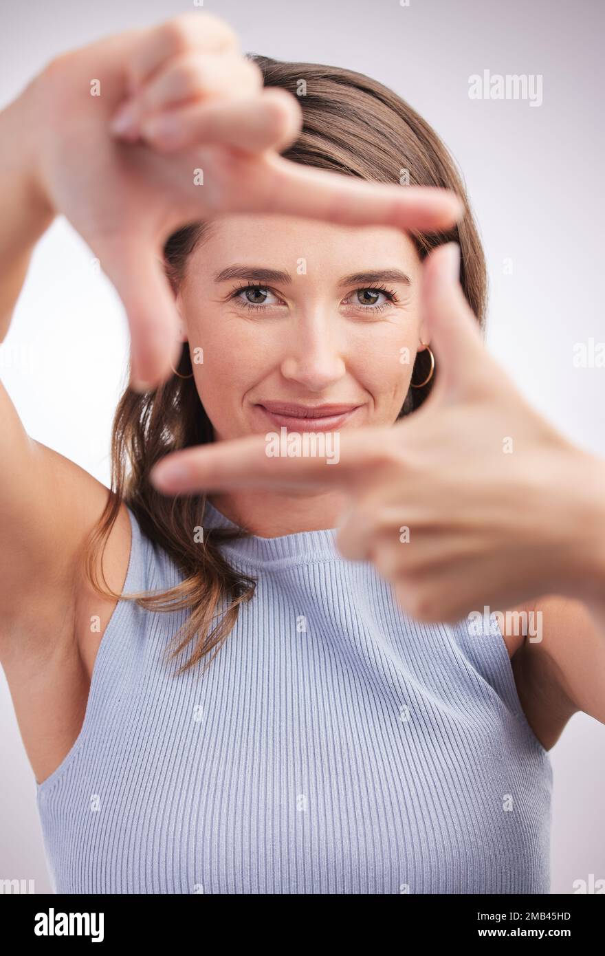 Halte die perfekte Pose für mich. Studioporträt einer jungen Frau, die einen Finger vor grauem Hintergrund umrahmt. Stockfoto
