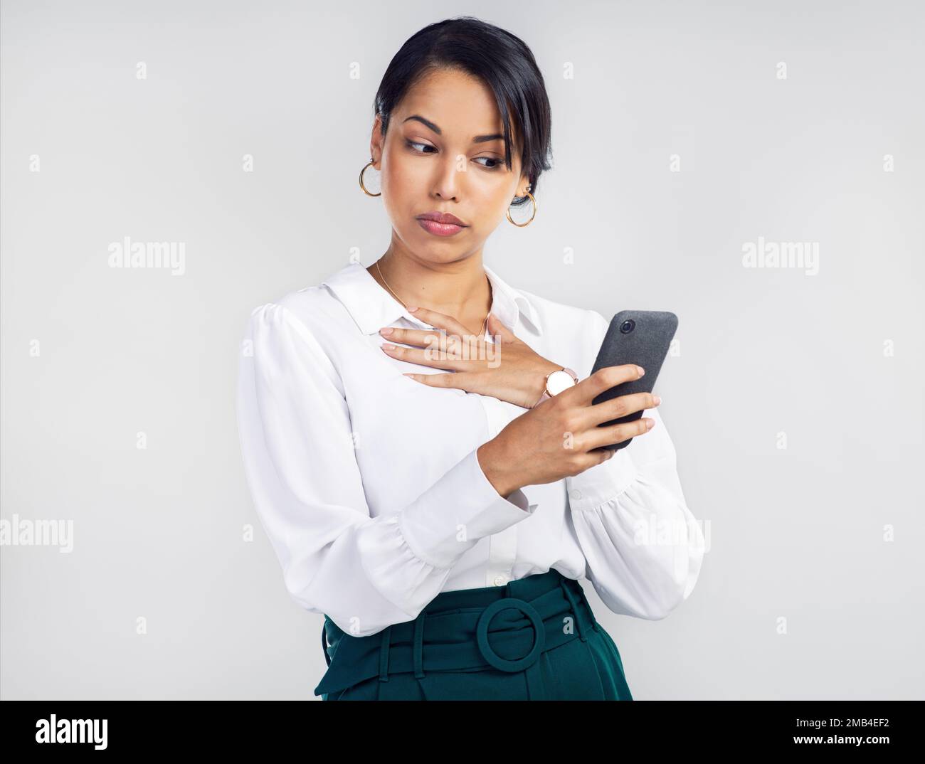 Nicht alle Social-Media-Inhalte waren gleich. Studiofoto einer jungen Geschäftsfrau, die ein Smartphone benutzt und unsicher vor grauem Hintergrund aussieht. Stockfoto