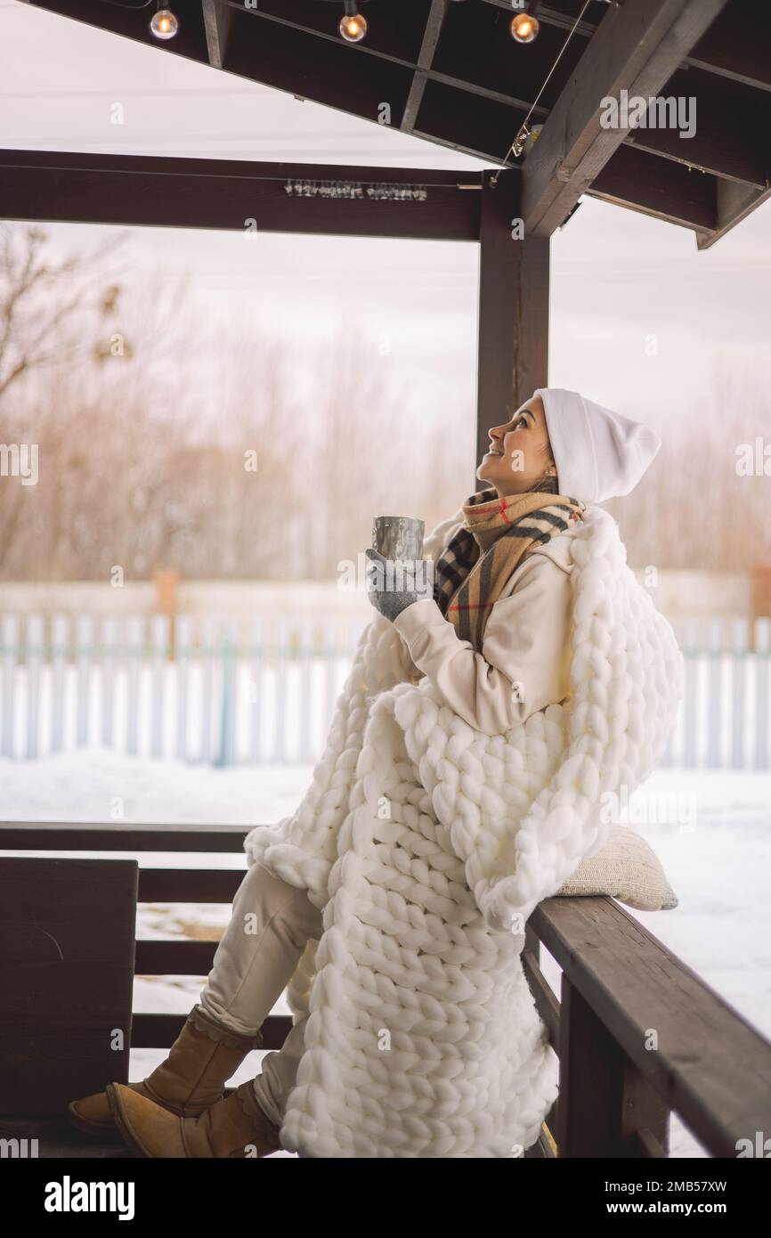 Entspannte Frau in warmen Winterkleidung Karomuster trinkt heißen Kakao Kaffee Tee im Freien Winter Natur Stockfoto