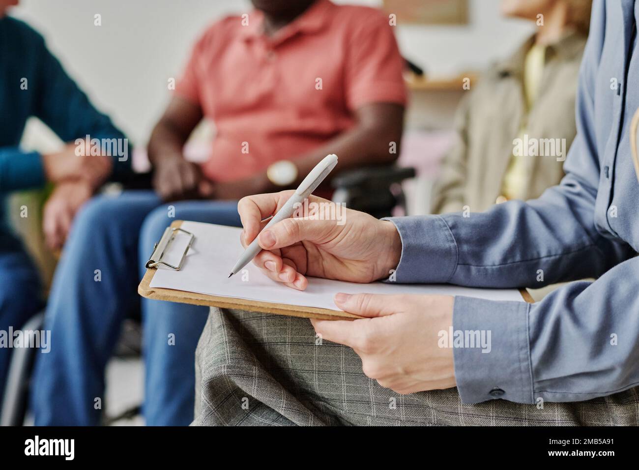 Nahaufnahme eines Psychologen, der während der Sitzung Notizen im Dokument macht Stockfoto