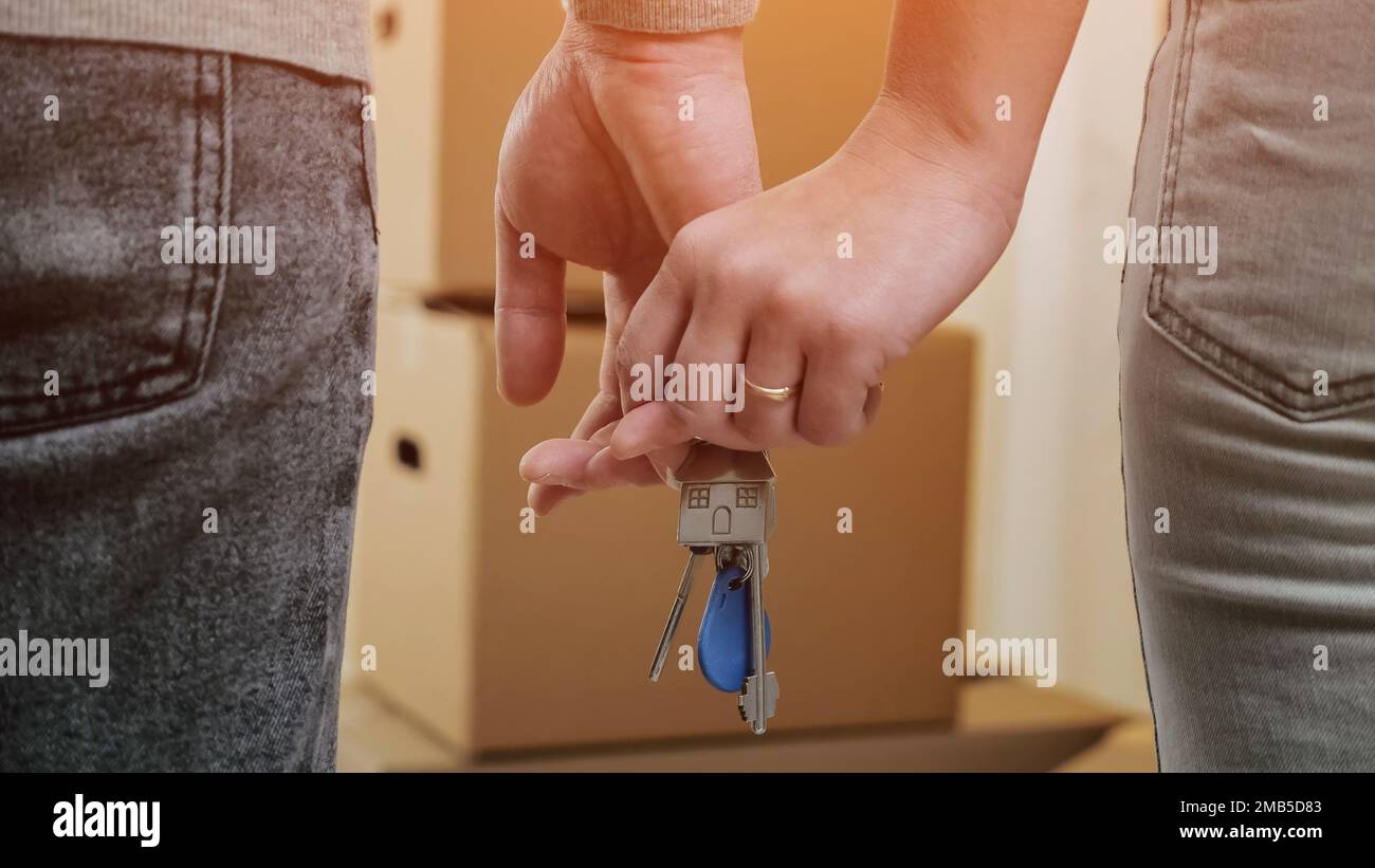 Das Ehepaar hält den Schlüssel zu flach und steht gegen ausgepackte Kisten Stockfoto