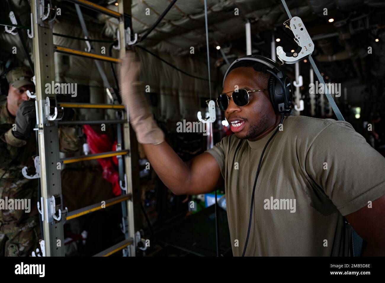 Ein flugmedizinischer Evakuierungsflugmann signalisiert, dass ein simulierter Patient an Bord eines C-130J Super Hercules geladen werden soll, um eine AE-Trainingsmission in Ceiba, Honduras, am 12. Juni 2022 vorzubereiten. Die Ausbildung ist Teil einer gemeinsamen Integrationsanstrengung IT Honduras, wo die Airmen mit lokalen Ersthelfern und Militärangehörigen an verschiedenen medizinischen Techniken und Verfahren arbeiten. Stockfoto