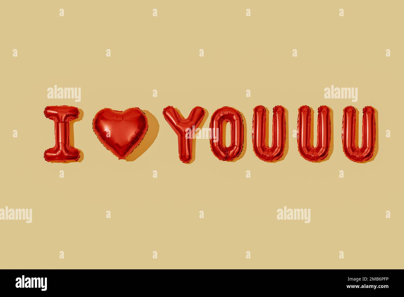 Ein paar Buchstabenballons, die den Satz "Ich liebe dich" bilden, auf einem blassgelben Hintergrund Stockfoto