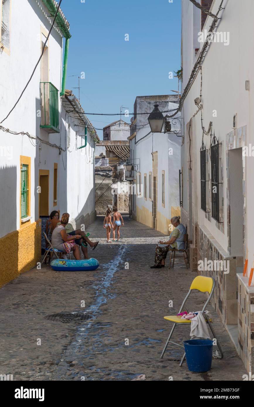 Blick auf die Straße in Jerez de la Frontera mit spielenden Kindern und Eltern an einem heißen Sommertag in Andalusien, Spanien. Stockfoto