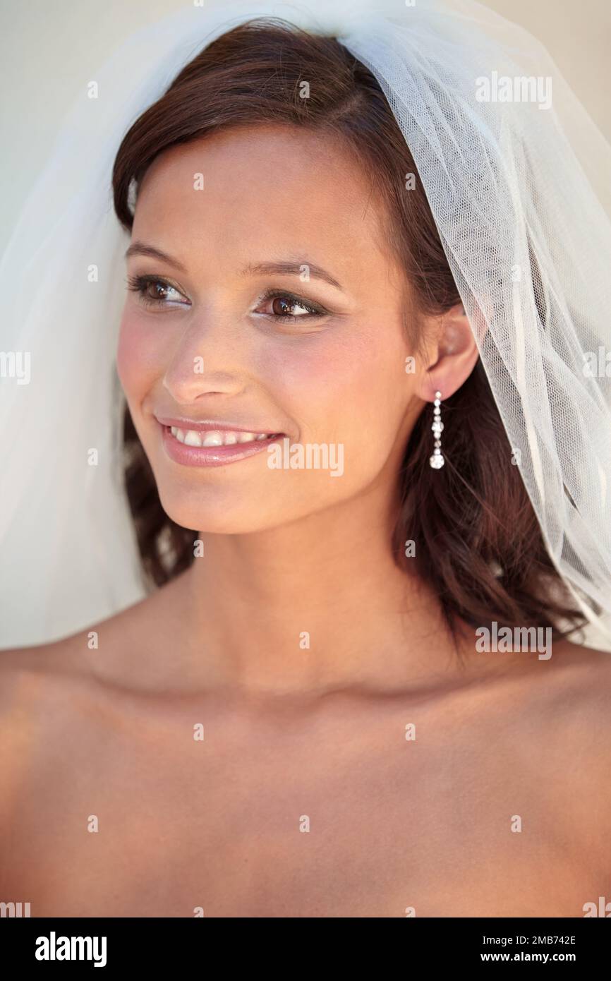 Brautvollkommenheit. Eine schöne Braut, die lächelt, während sie ihren Schleier trägt. Stockfoto
